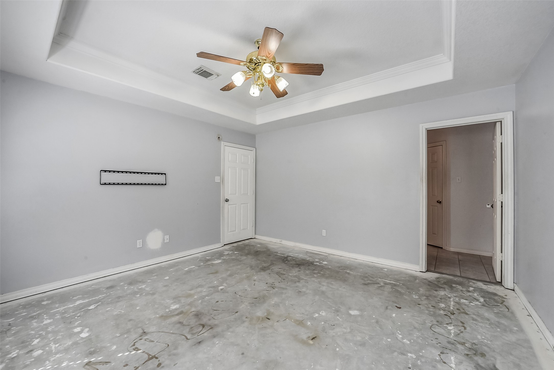 The spacious primary bedroom offers a peaceful retreat with a tray ceiling, crown molding, and a ceiling fan. This room is waiting for your choice of flooring.