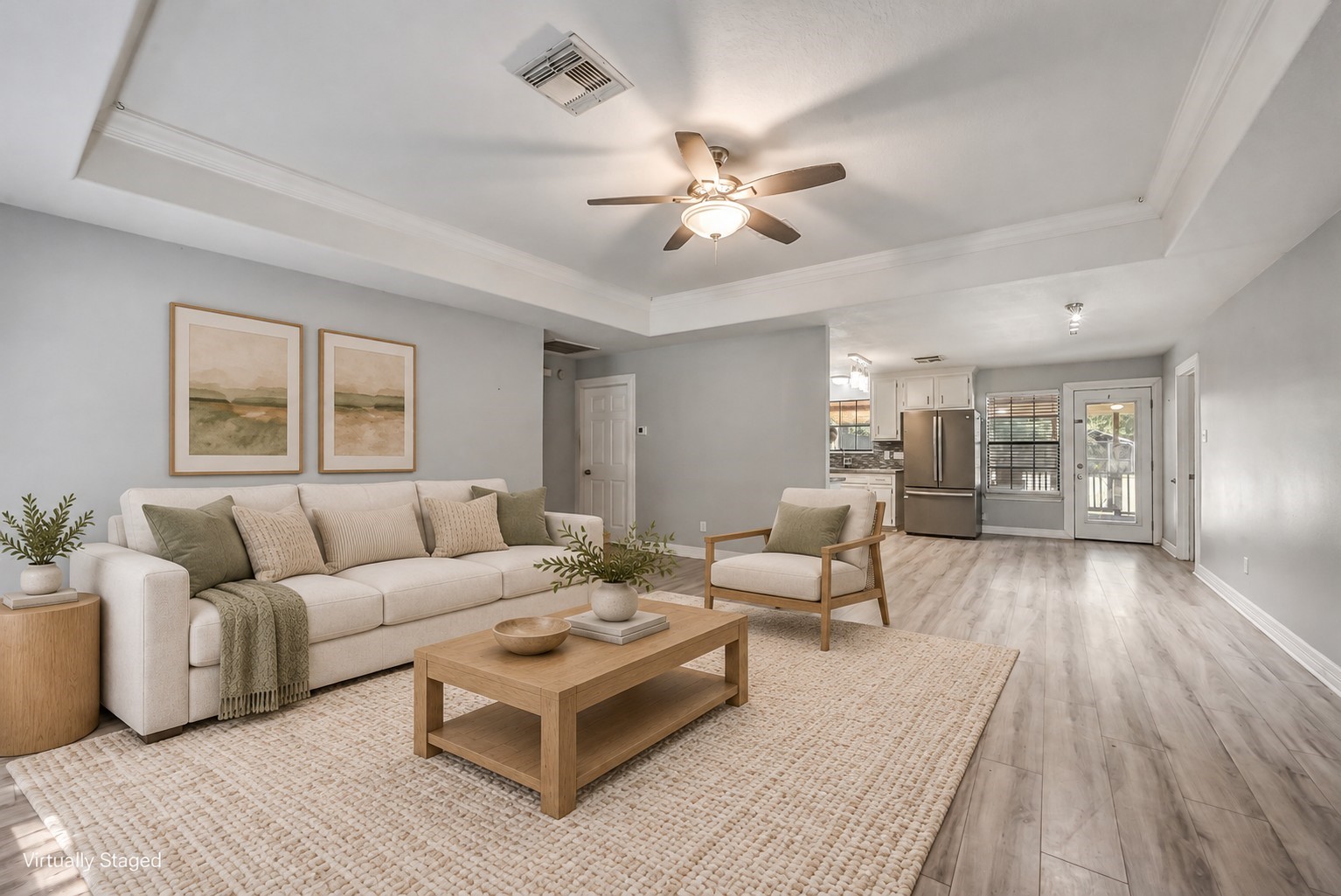 This inviting family room features a tray ceiling accented with crown molding, a ceiling fan, and abundant natural light.  This photo is virtually staged.