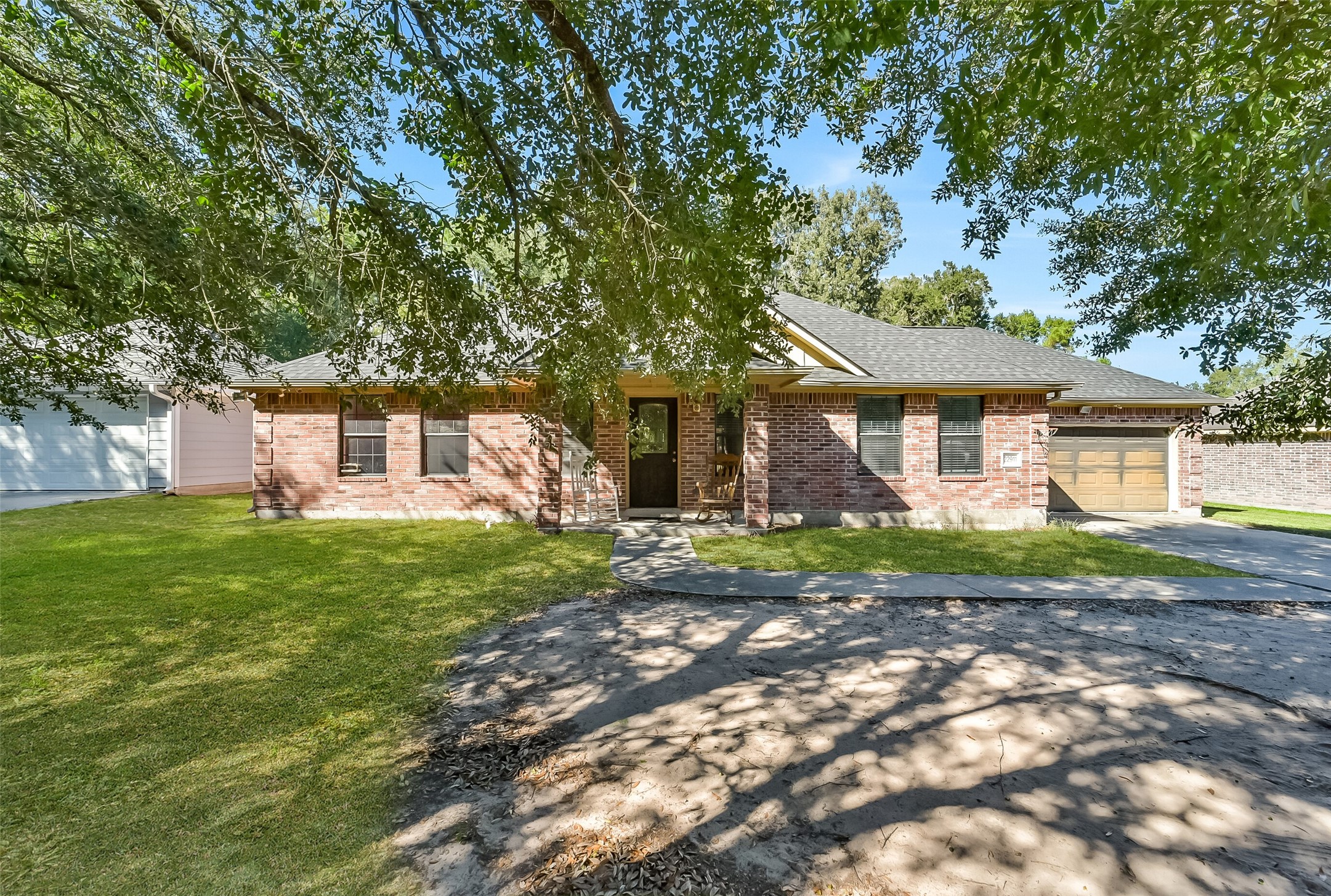 Nestled beneath mature shade trees, this charming one-story brick home offers three bedrooms, two full bathrooms, and a two-car garage.