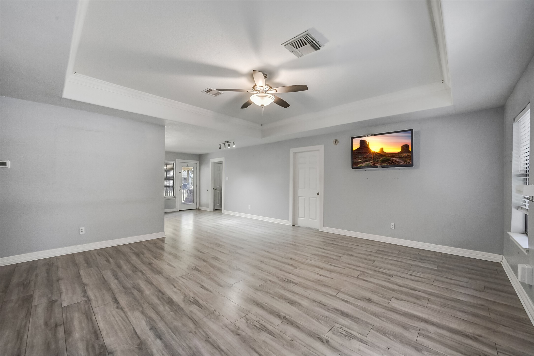 Neutral tones and wood-look flooring create a warm, cohesive setting, while the spacious layout offers a comfortable gathering space for everyday living and entertaining.