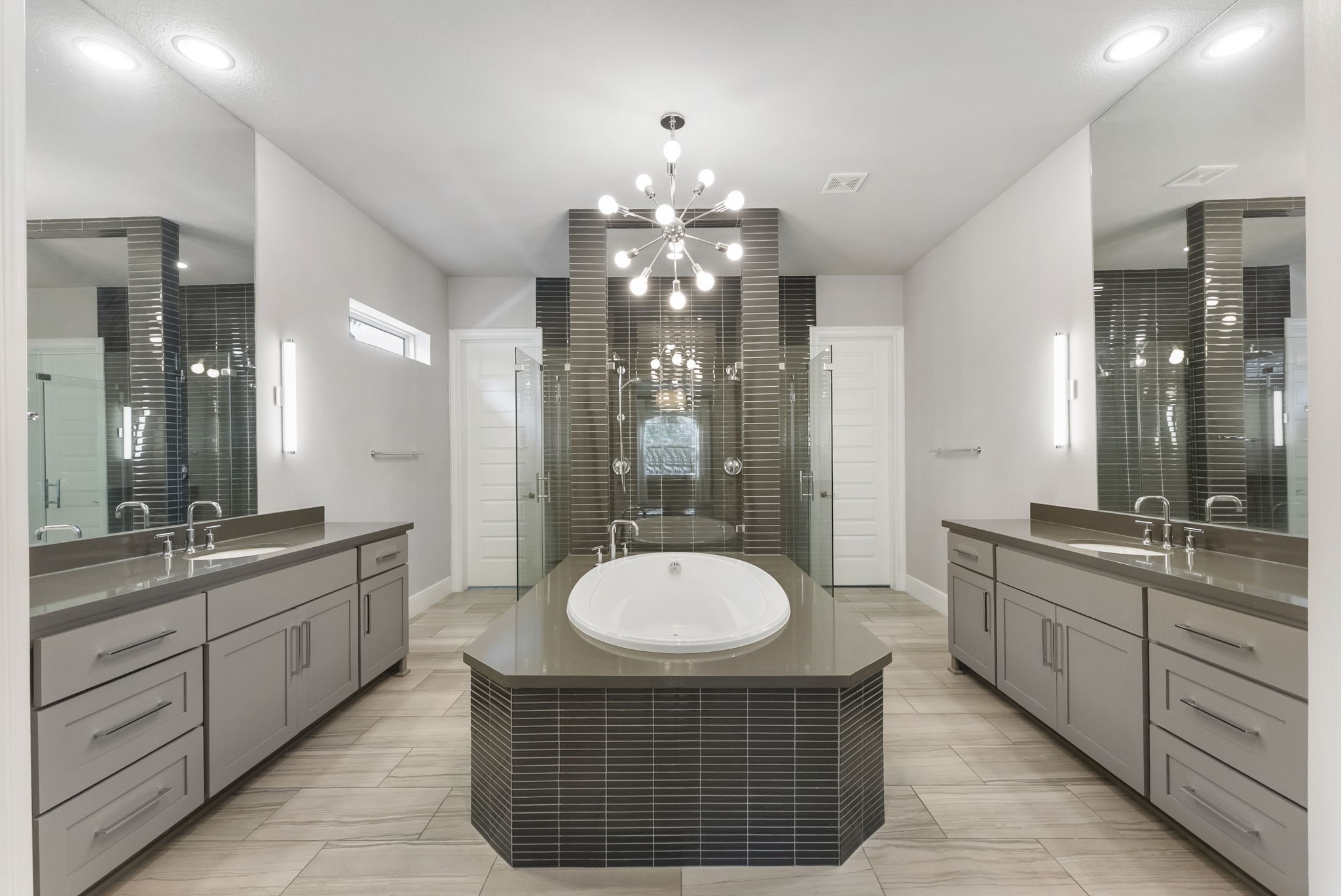 Primary bathroom featuring custom lighting, dual sinks, and abundant cabinetry.