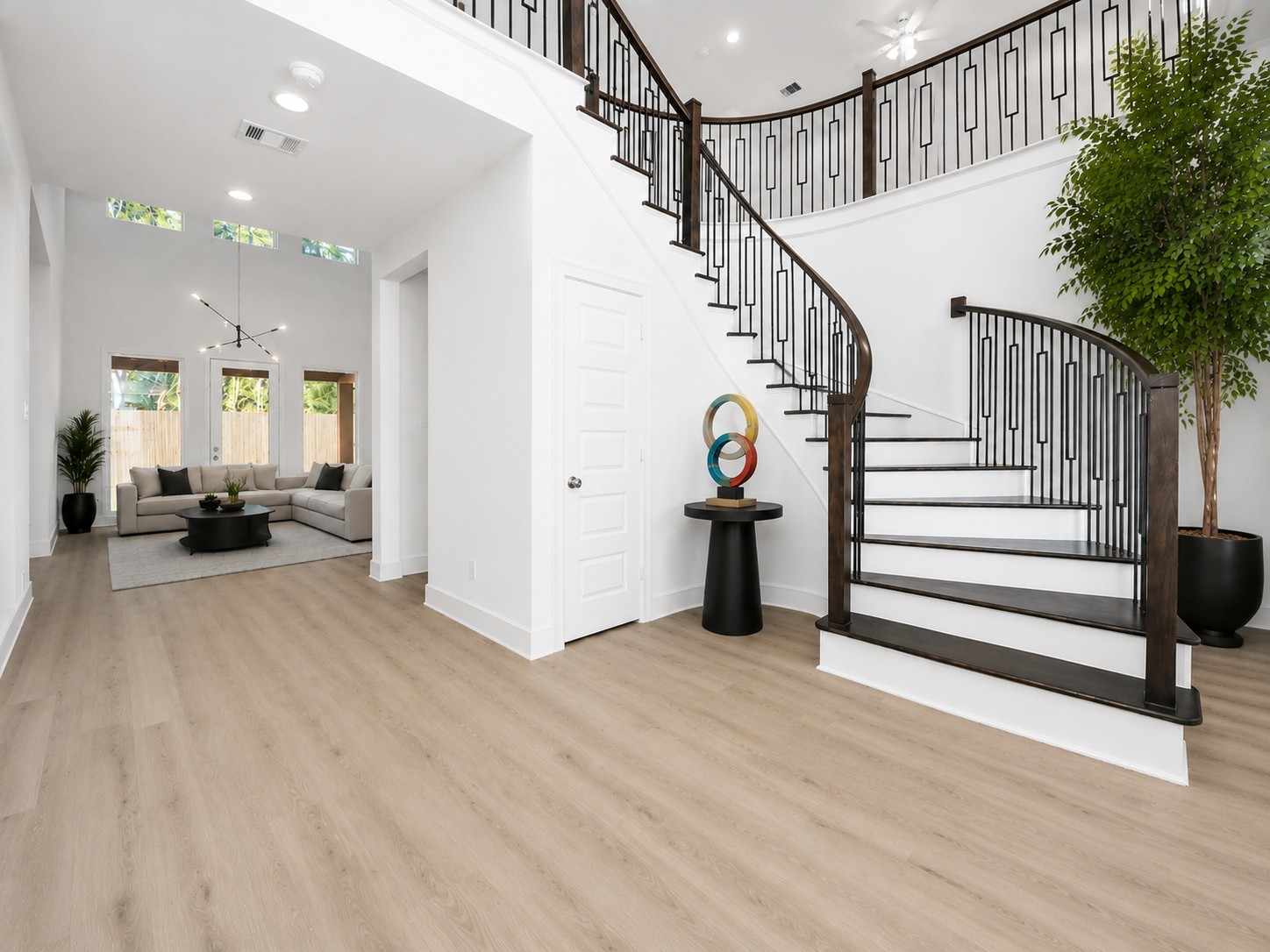 Grand formal entryway w/sweeping staircase w/real wood treads and contemporary spindles. Virtually staged floor plants and furniture and contemporary light fixture in ivingroom.
