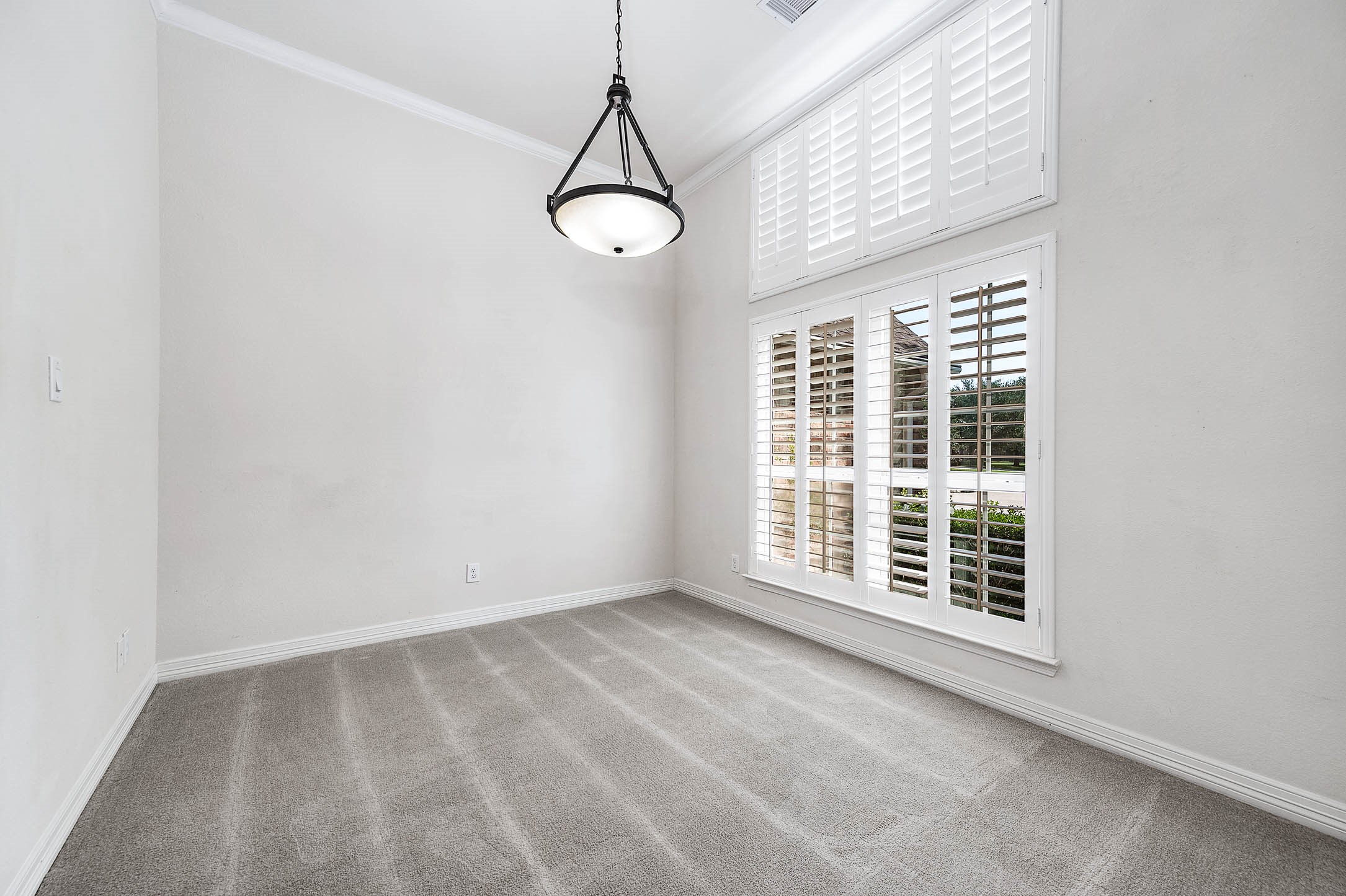 The formal dining room, adorned with elegant plantation shutters, offers a stunning view of the front of the property.