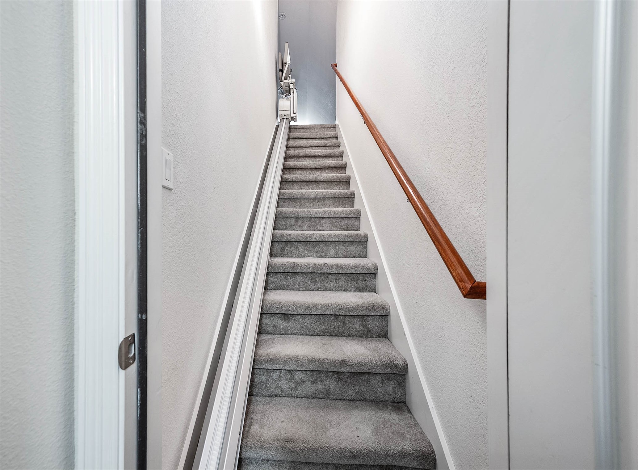 Carpeted staircase with a wooden handrail leads to the upper level, offering a cozy and secure ascent.