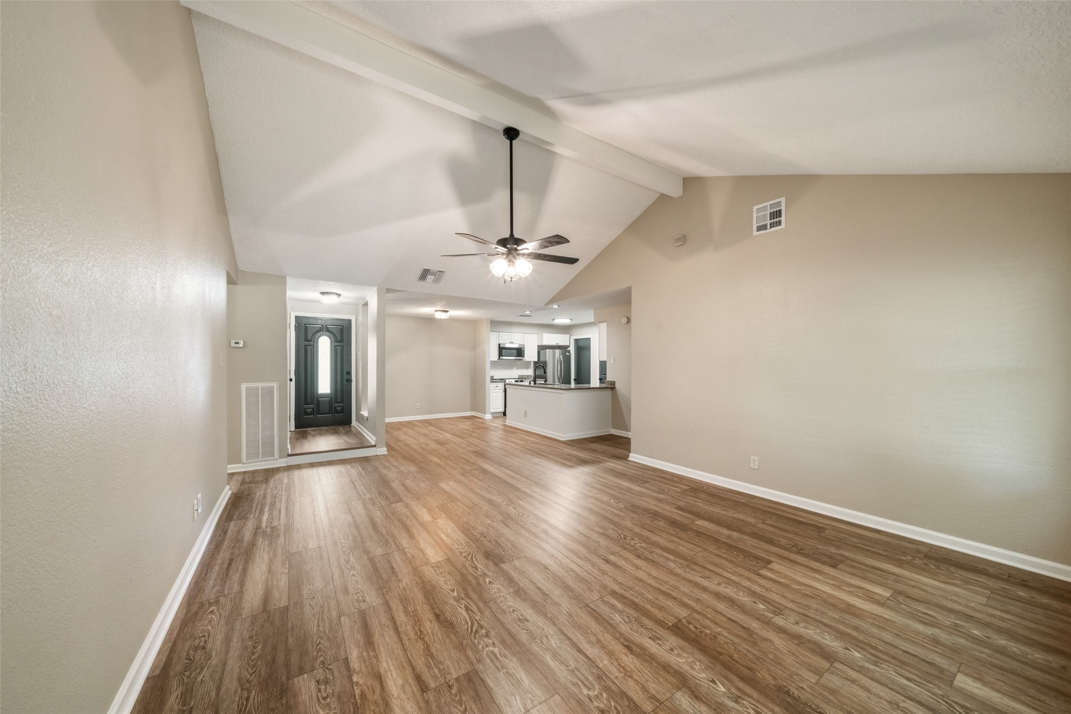 View of living room, dining area, and kitchen from the back door