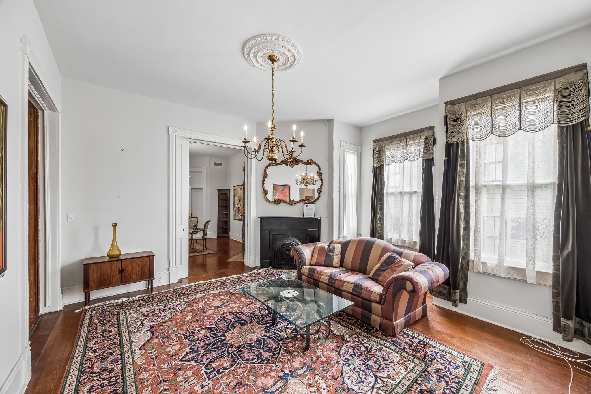 The formal living room filled with natural light. All the celings are 12 feet high. Elegant modern brass chandelier that fits this period home.