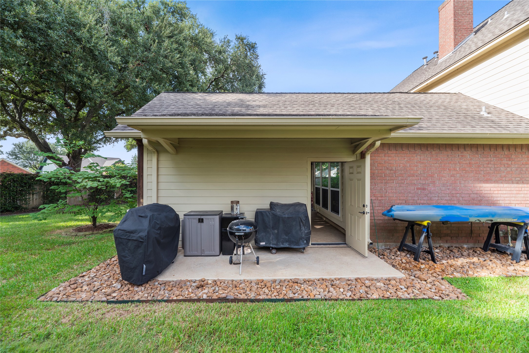 Private backyard space featuring a covered patio area perfect for grilling and outdoor storage.