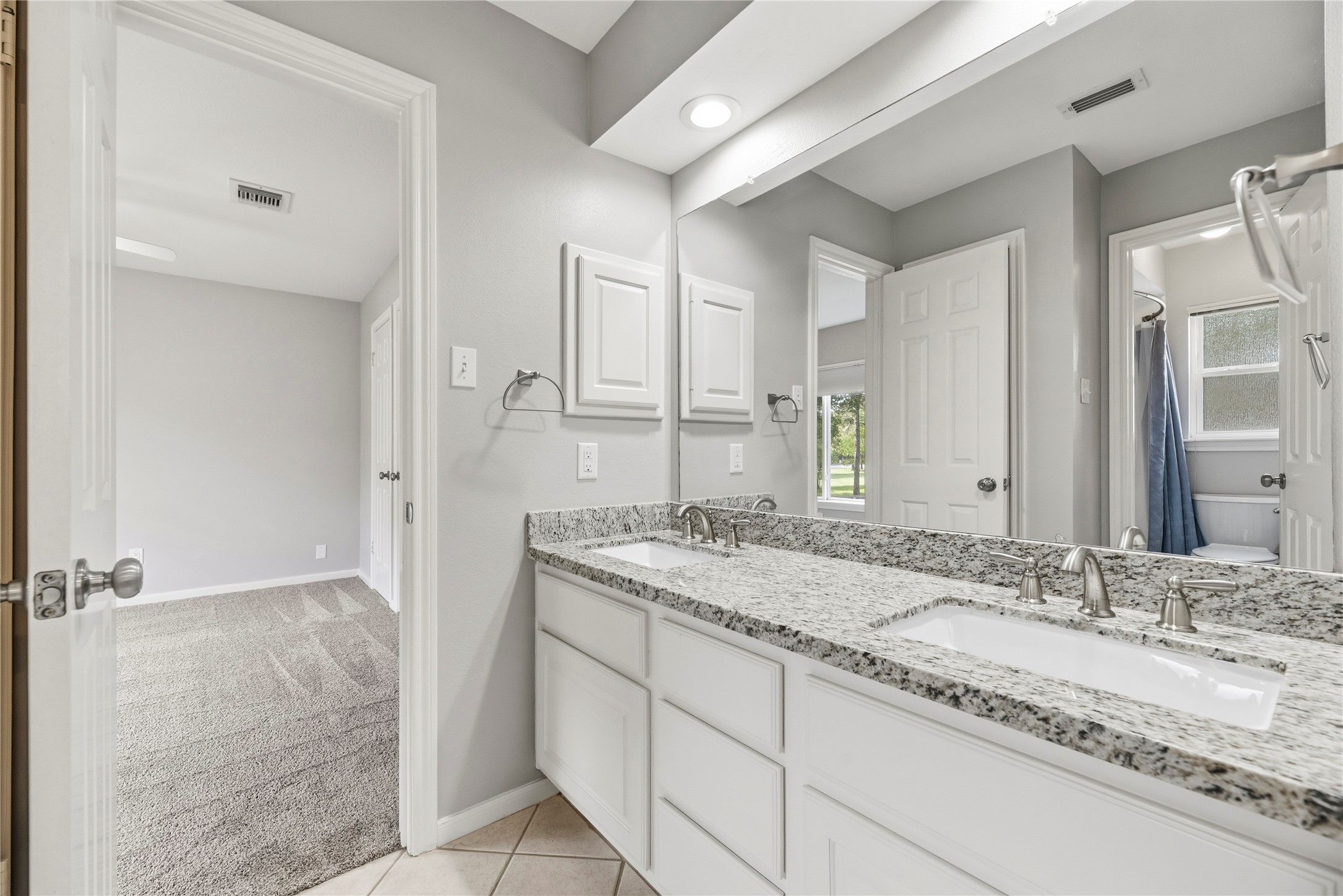 A Jack-and-Jill-style bathroom featuring a dual-sink vanity with granite countertops.