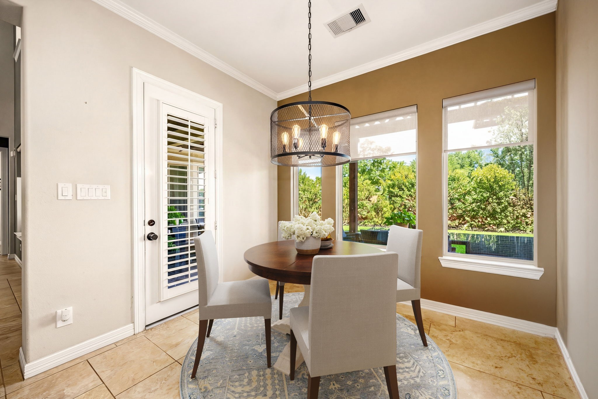 The sweetest spot in the house! This charming breakfast nook features a stylish drum pendant light, crown molding, and oversized windows with serene backyard view,  the perfect place to start your day. *Virtually Staged