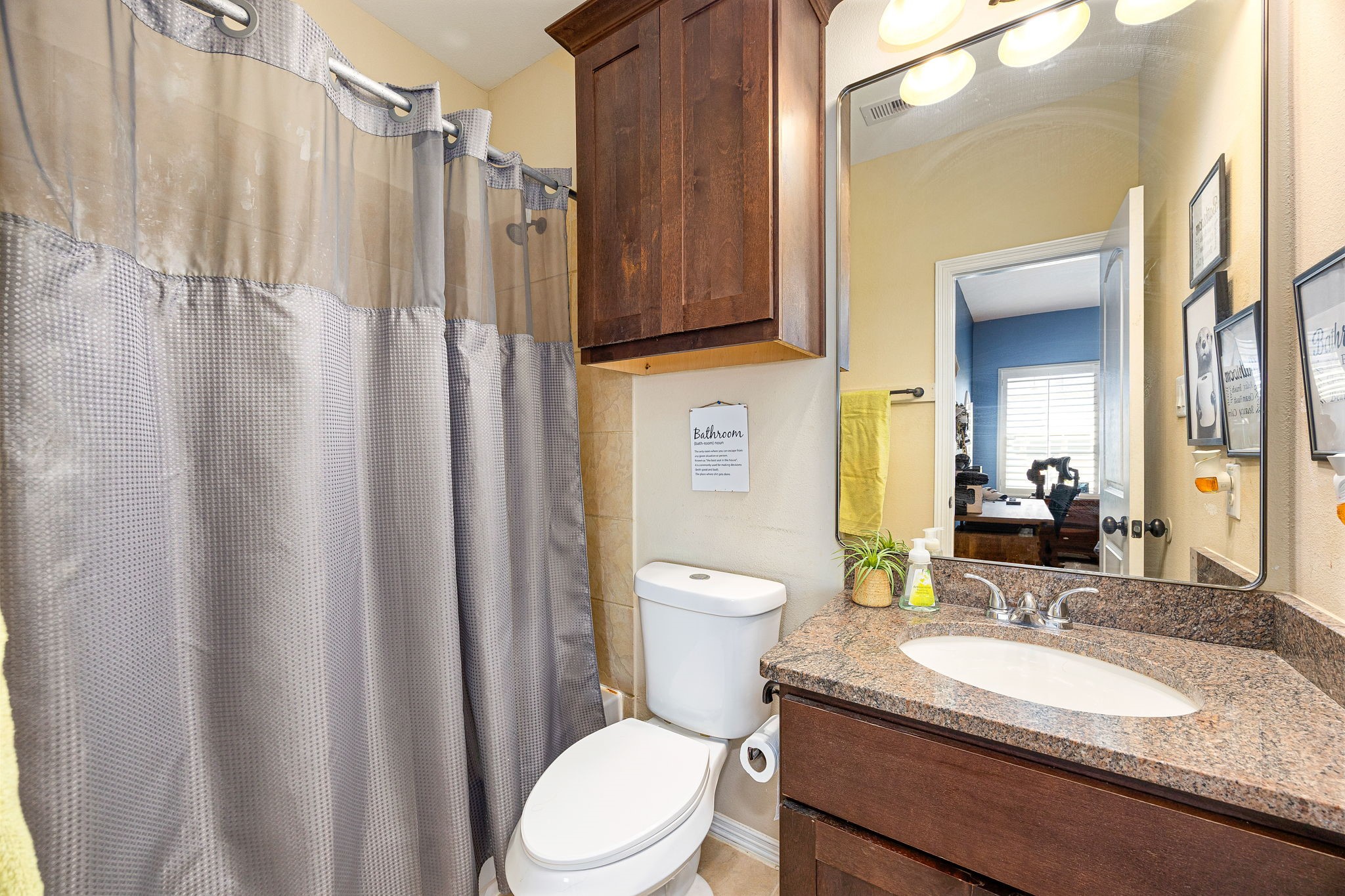 Clean and functional! This secondary bath features granite countertops, dark wood cabinetry, a large vanity mirror, and a tub/shower combo, everything you need! *Virtually Staged