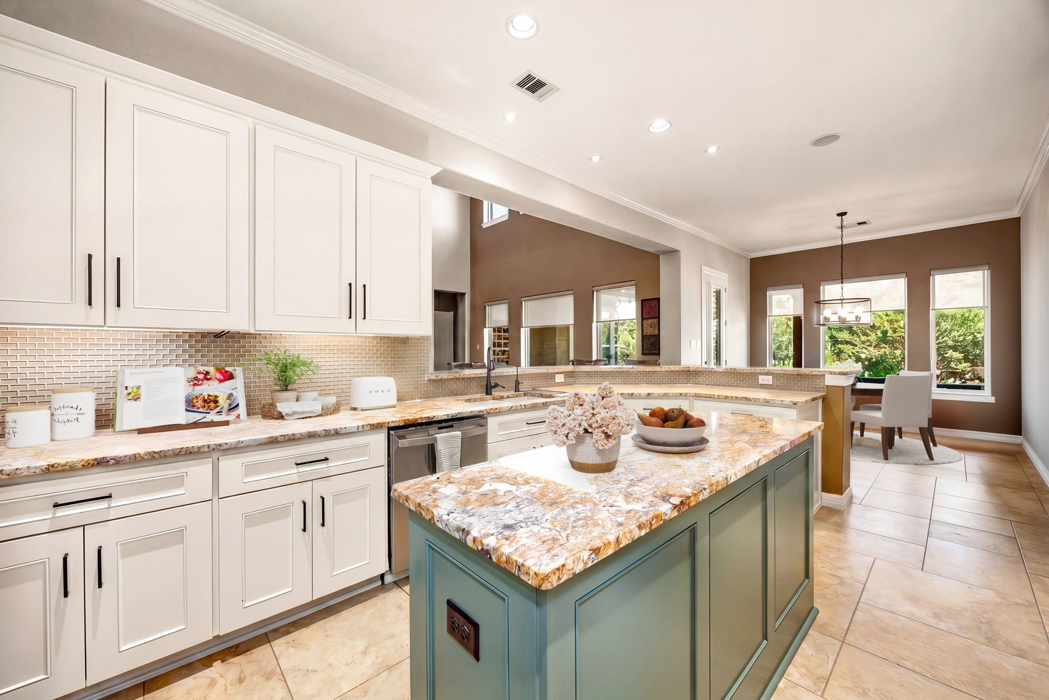 A chef's dream! This stunning kitchen features white cabinetry with black hardware, an eye-catching sage green island, gorgeous granite countertops, mosaic tile backsplash, and an open flow into the breakfast room. Bright, beautiful, and built for entertaining! *Virtually Staged