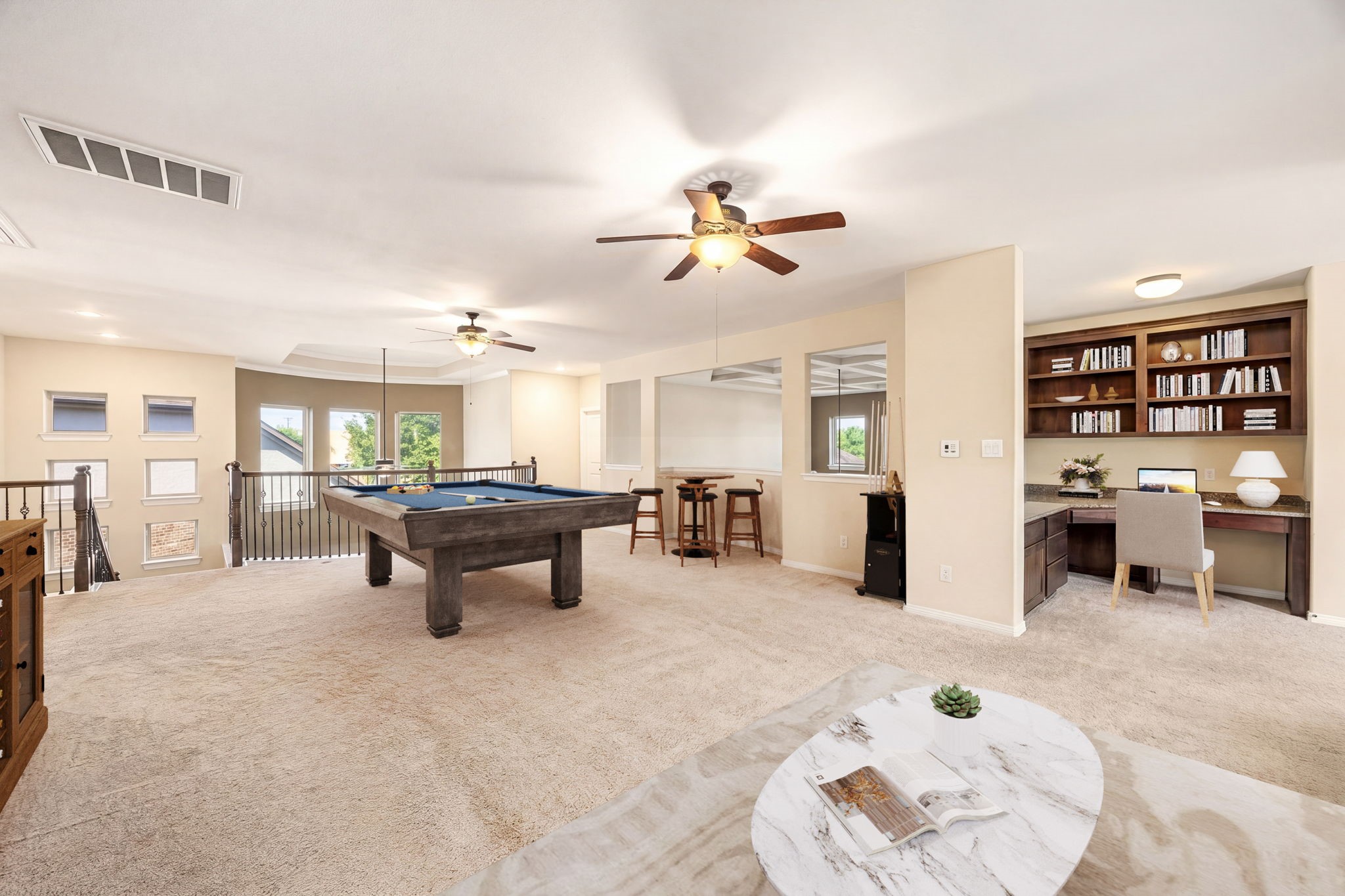 This oversized game room features a pool table, built-in bookshelves, a dedicated study nook, bar seating, and an iron-railed overlook, entertaining and productivity all in one! *Virtually Staged