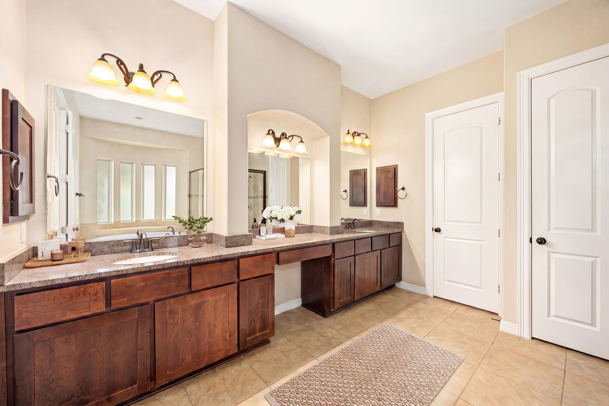 Get ready in style! The primary bath boasts dual vanities with rich wood cabinetry, granite countertops, and elegant vanity lighting, his and hers never looked so good.