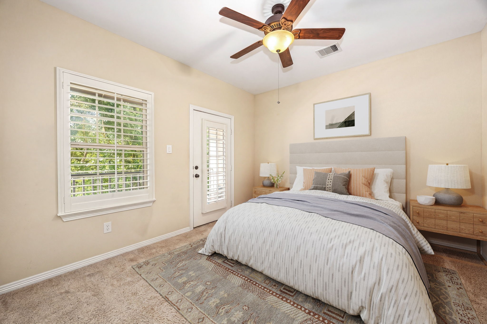 This bright secondary bedroom features plush carpet, plantation shutters, a ceiling fan, and direct access to the balcony through a charming French door, such a unique and special touch! *Virtually Staged
