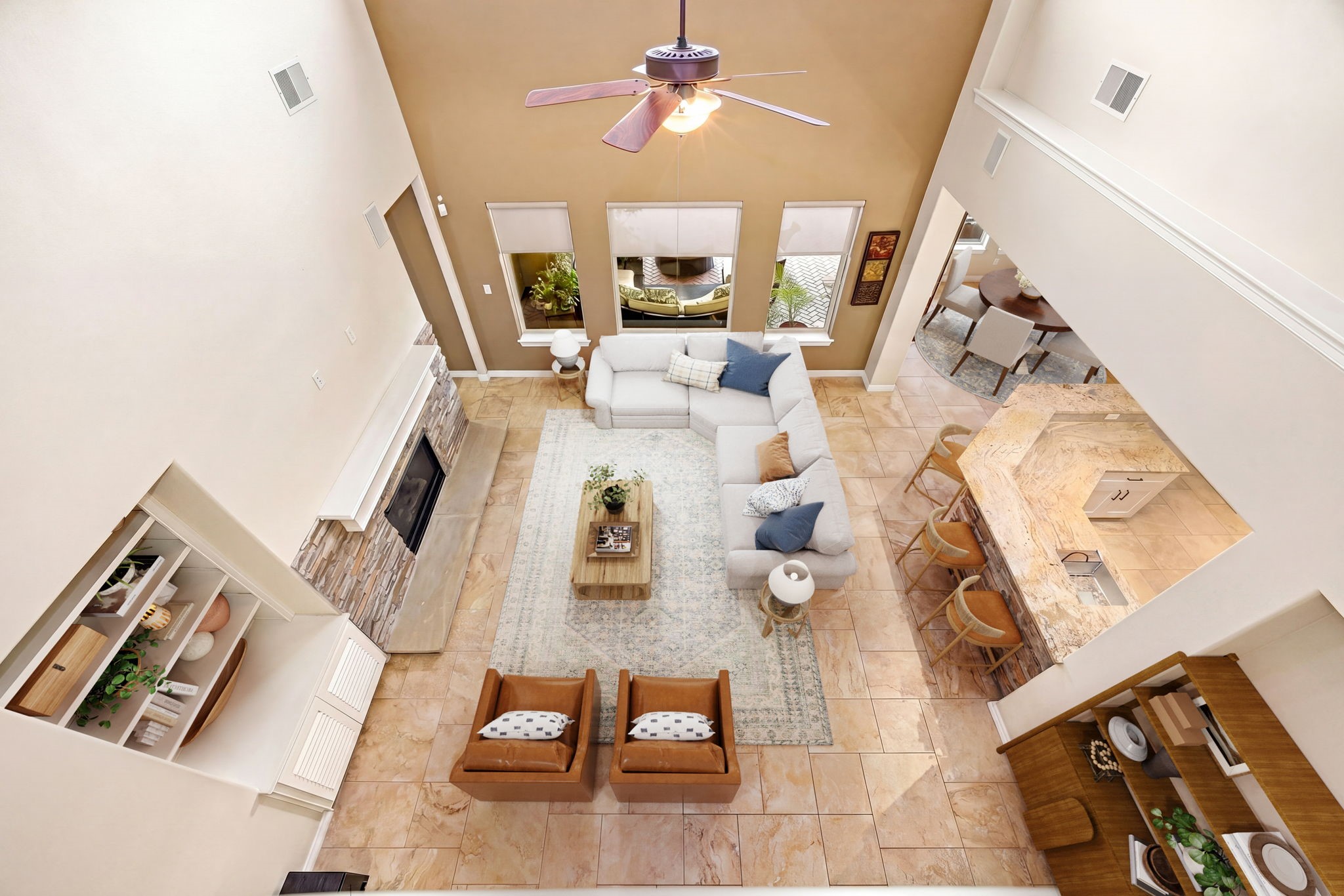 This stunning bird's eye shot shows just how grand and open this floor plan truly is, soaring two-story ceilings, stacked stone fireplace, built-in shelving, and a seamless flow into the kitchen and dining area. Space, style, and function all in one! *Virtually Staged