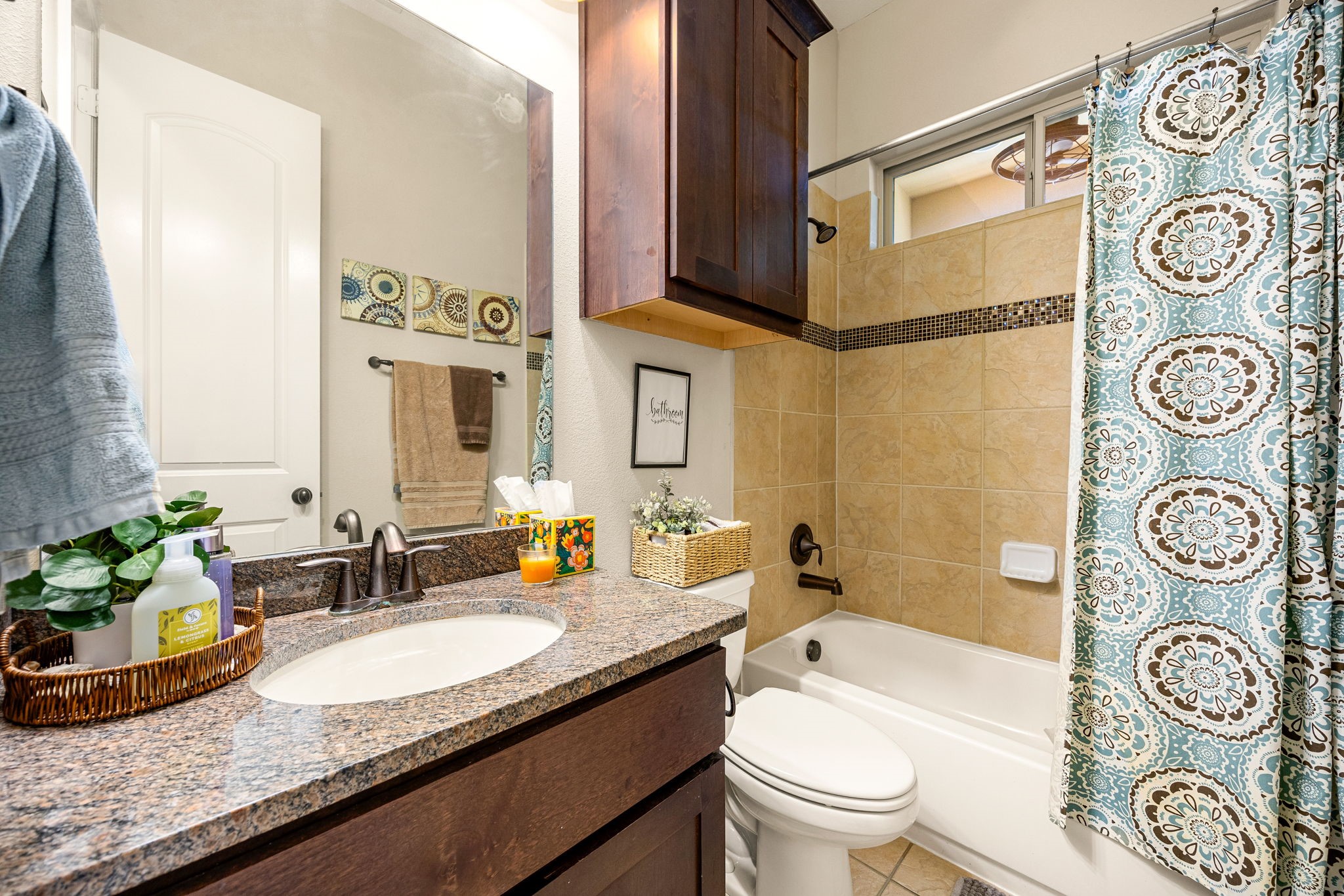 Cute and functional! This first floor bath features granite countertops, dark wood cabinetry, tile tub surround with mosaic accent, and plenty of storage.