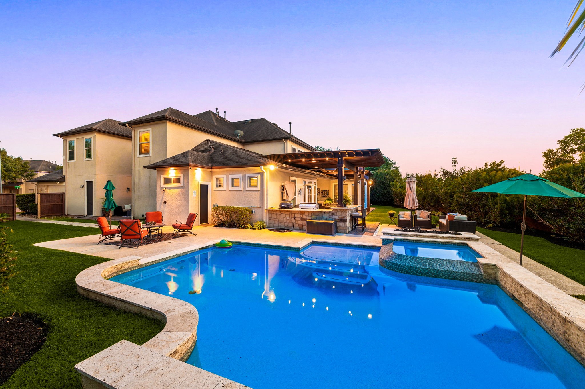 Your own backyard paradise! This stunning pool and spa glow beautifully at dusk, surrounded by a travertine deck, lush landscaping, covered pergola, and outdoor kitchen, resort-style living every single day!