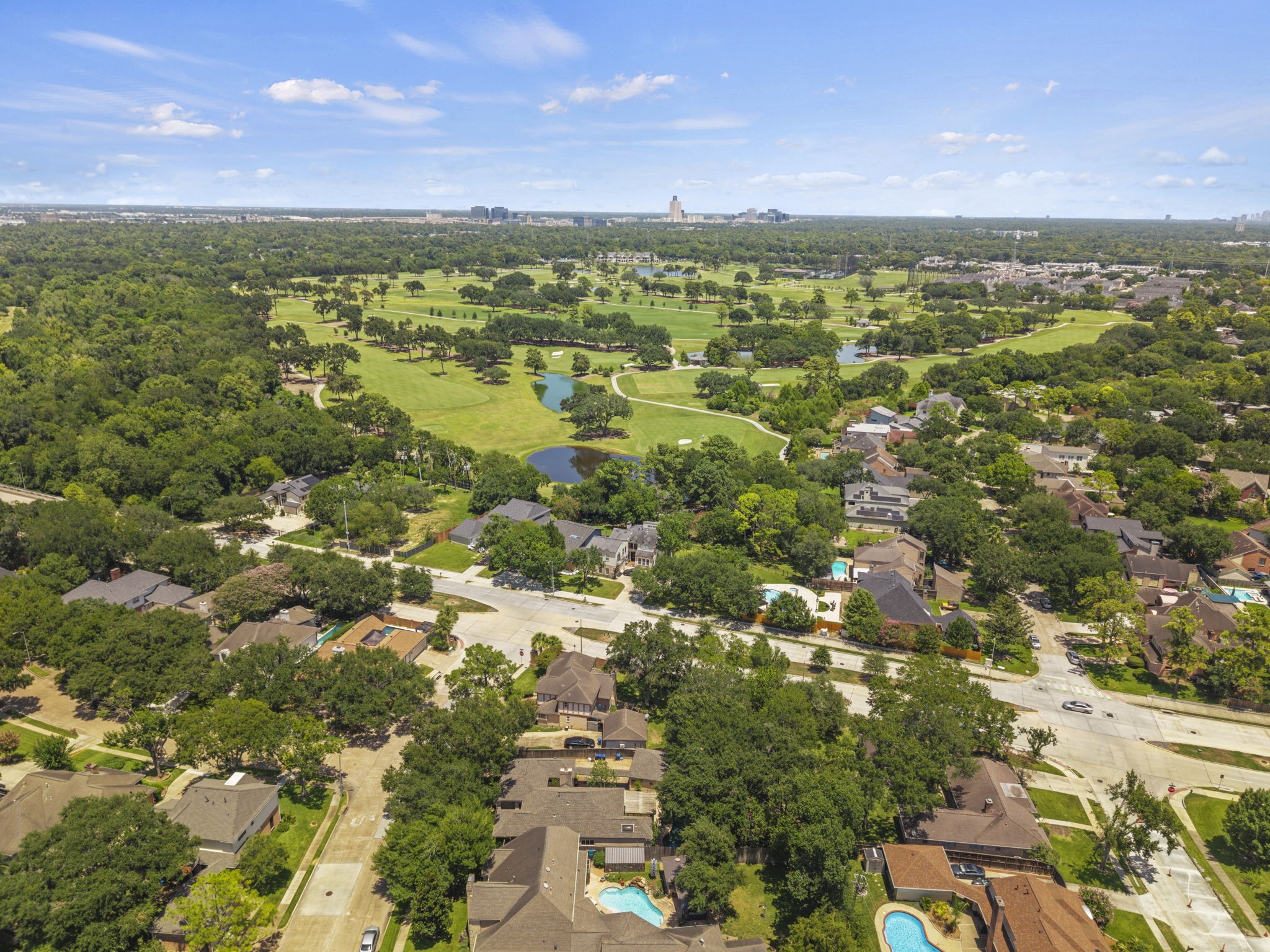 The aerial view captures the homes Energy Corridor setting, mature surroundings, and proximity to green space. It gives context to the propertys location near Terry Hershey Park and the surrounding Woods Lakeside area.