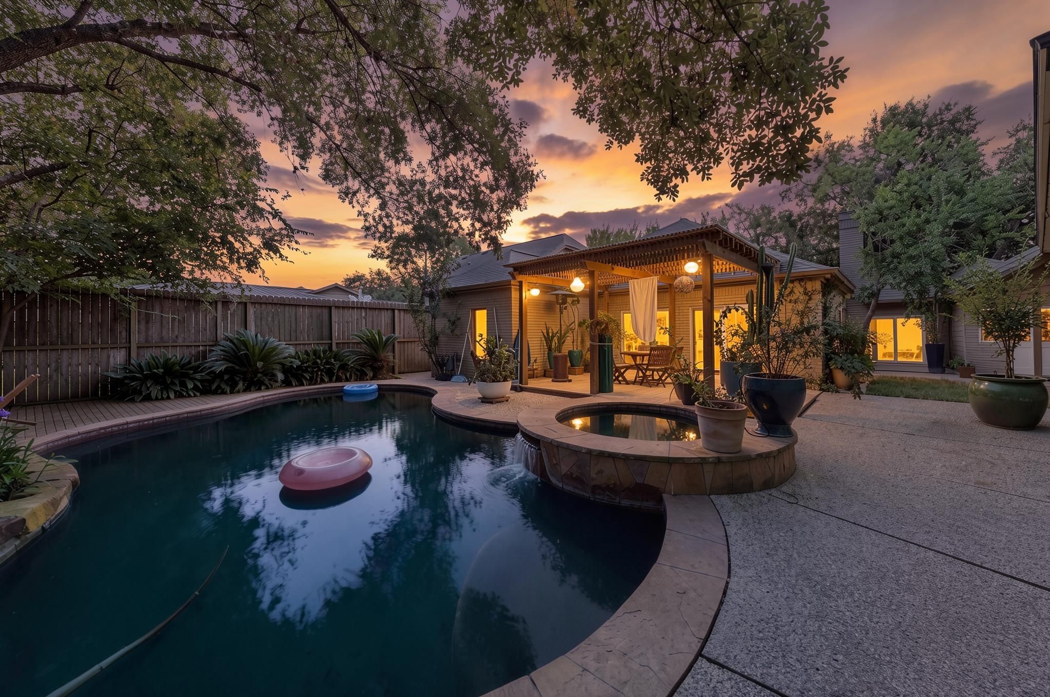 The backyard pool creates a private retreat with a shaded setting, attached hot tub, and mature landscaping surrounding the space. The evening view gives the outdoor area a calm, resort-style presence. - Virtually enhanced