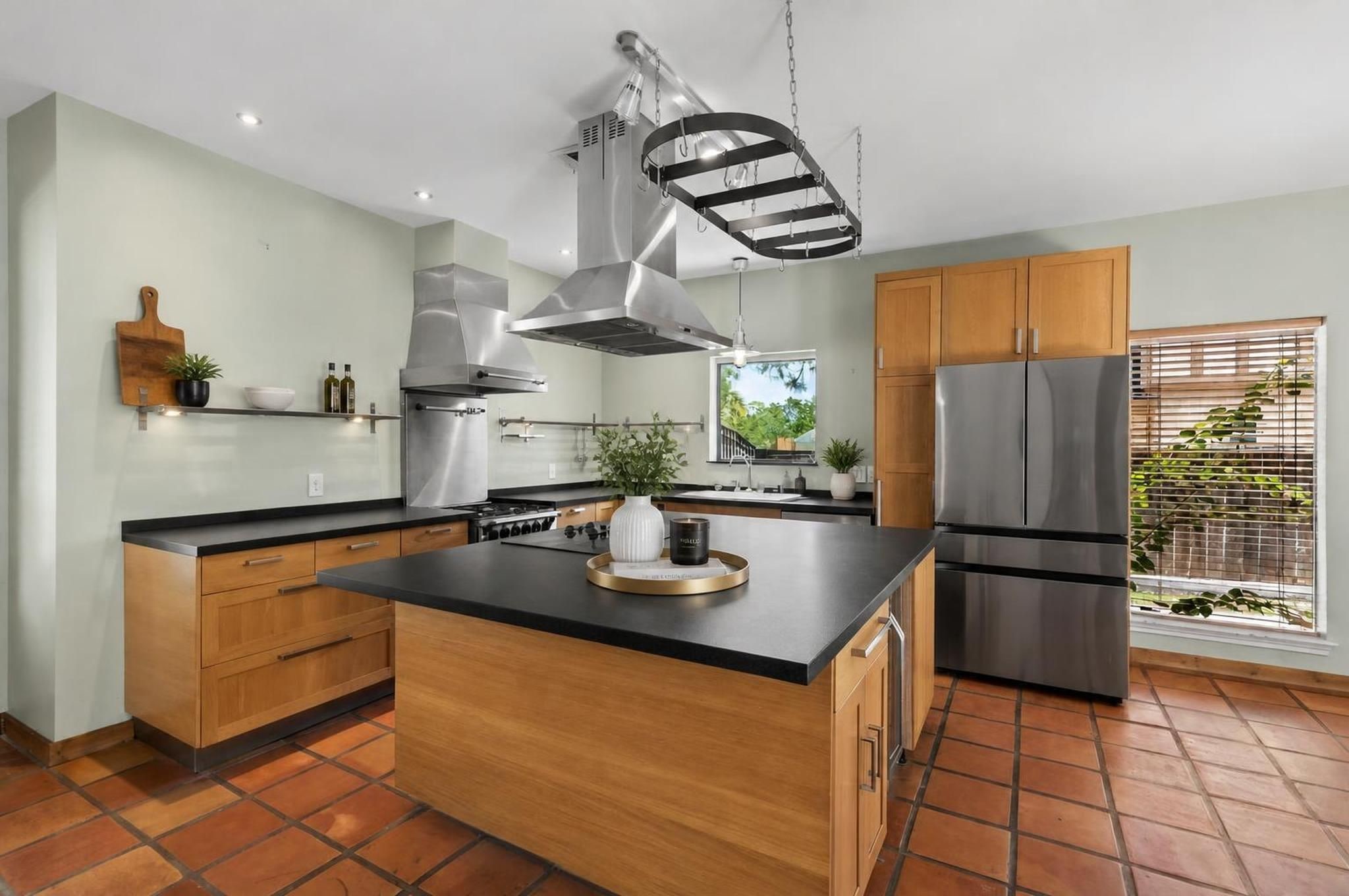 The remodeled kitchen centers around a massive honed granite island with cooktop, breakfast bar seating, two ovens, pantry storage, and a wine/beverage fridge. The space is designed as one of the strongest features of the home.