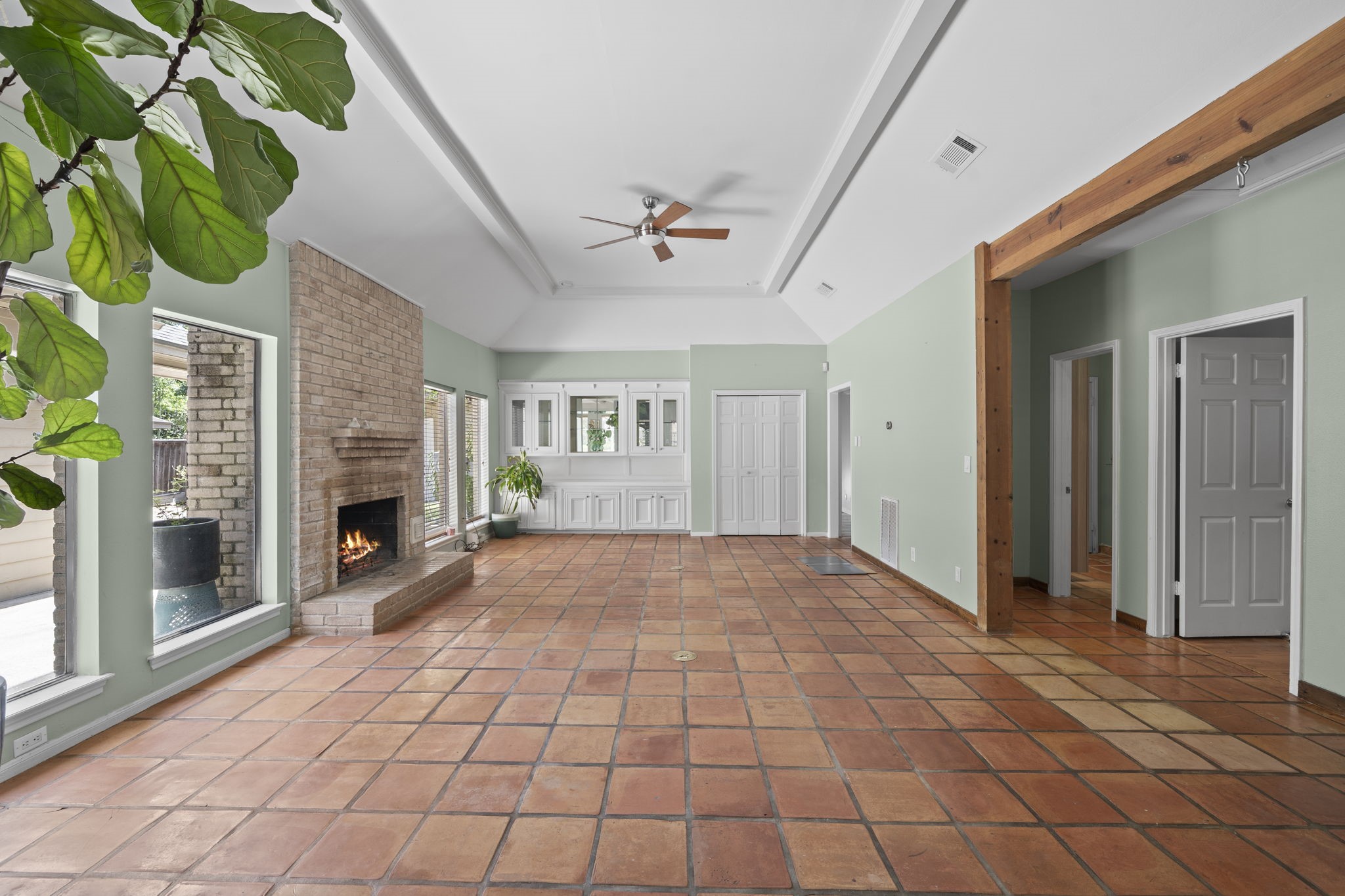 The unfurnished living room highlights the vaulted ceiling, fireplace placement, wood flooring, and generous proportions. The space is open, bright, and directly connected to the kitchen and dining areas.