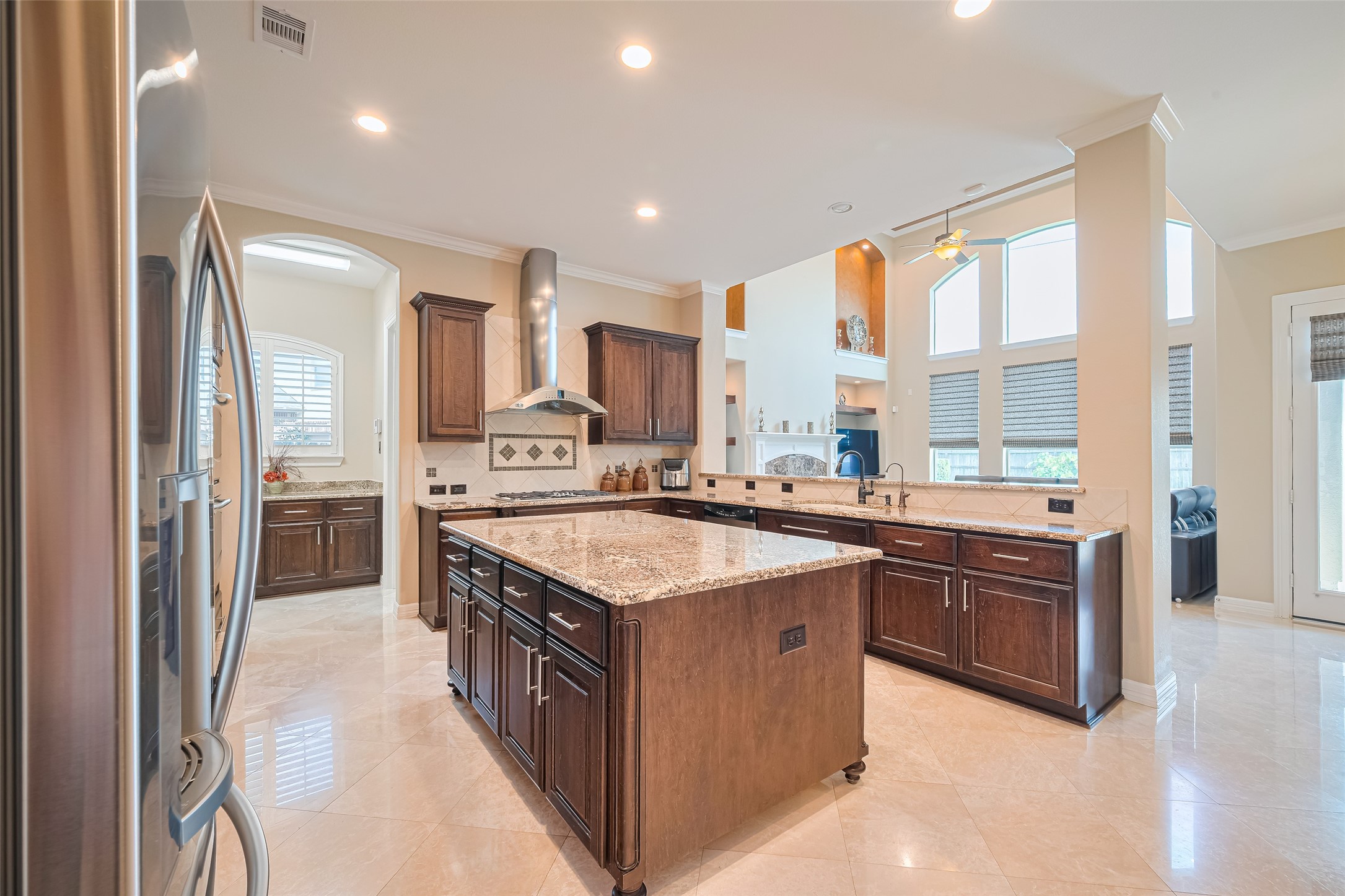 Alternate kitchen angle emphasizing the oversized granite island, extensive storage, and open sightline into the two-story family room.