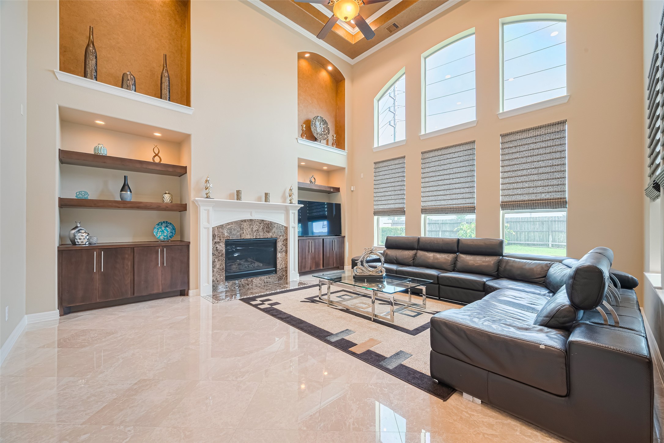 Soaring two-story family room anchored by a fireplace, custom built-ins, and a dramatic wall of windows filling the space with natural light.