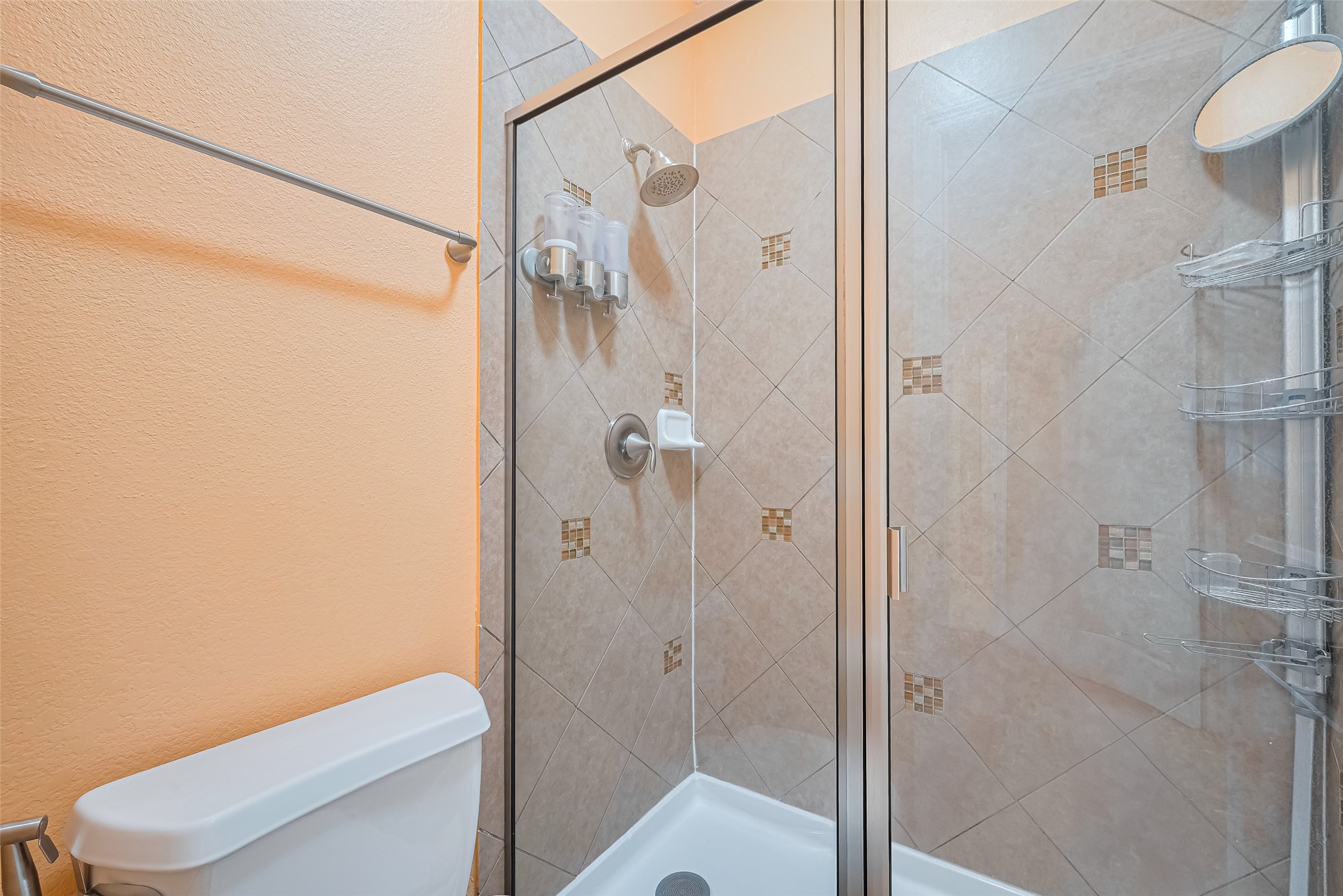 Tiled fourth bathroom shower featuring decorative accent details and a sleek glass enclosure.