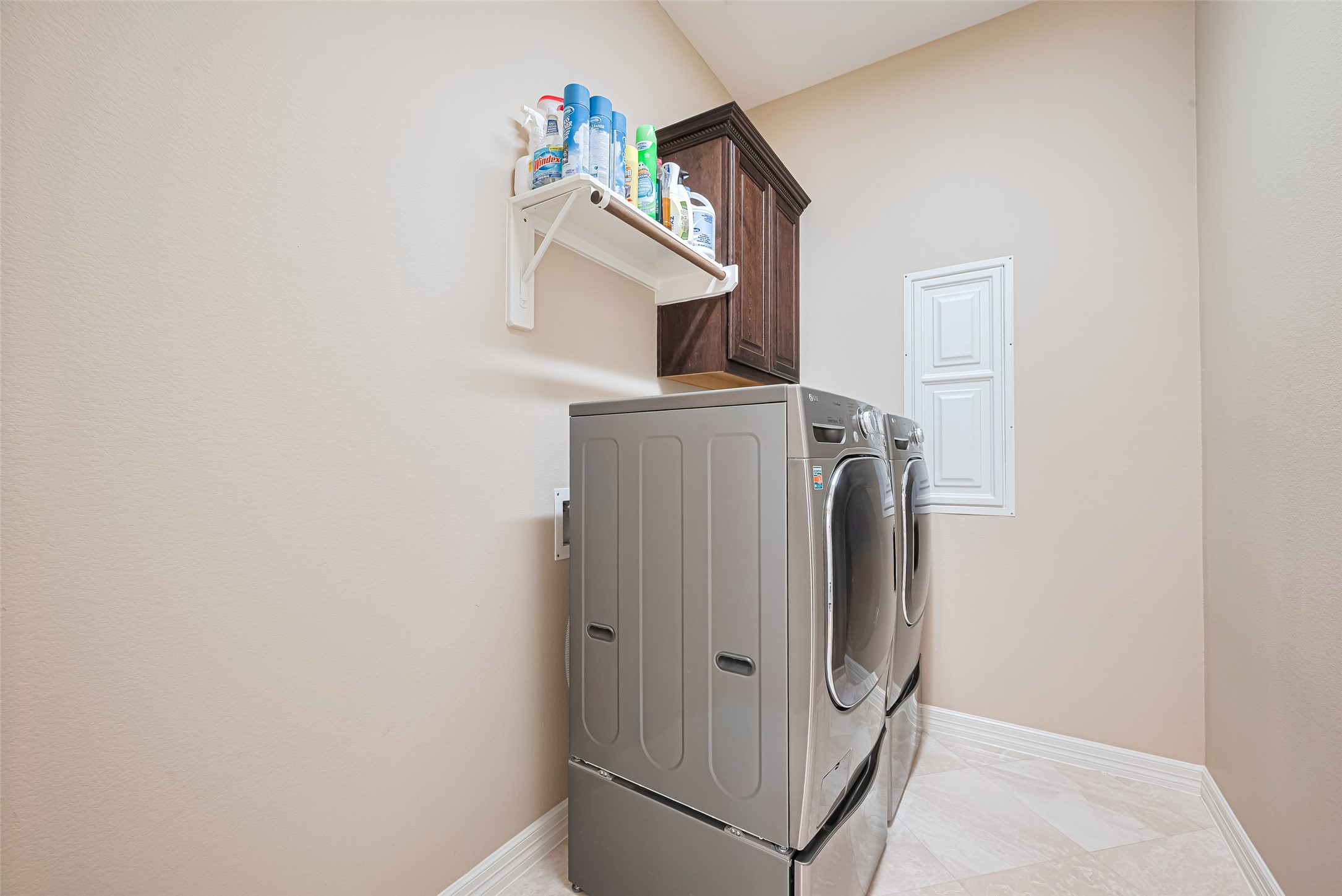 Dedicated laundry room featuring side-by-side washer and dryer, built-in cabinetry, and convenient overhead storage.