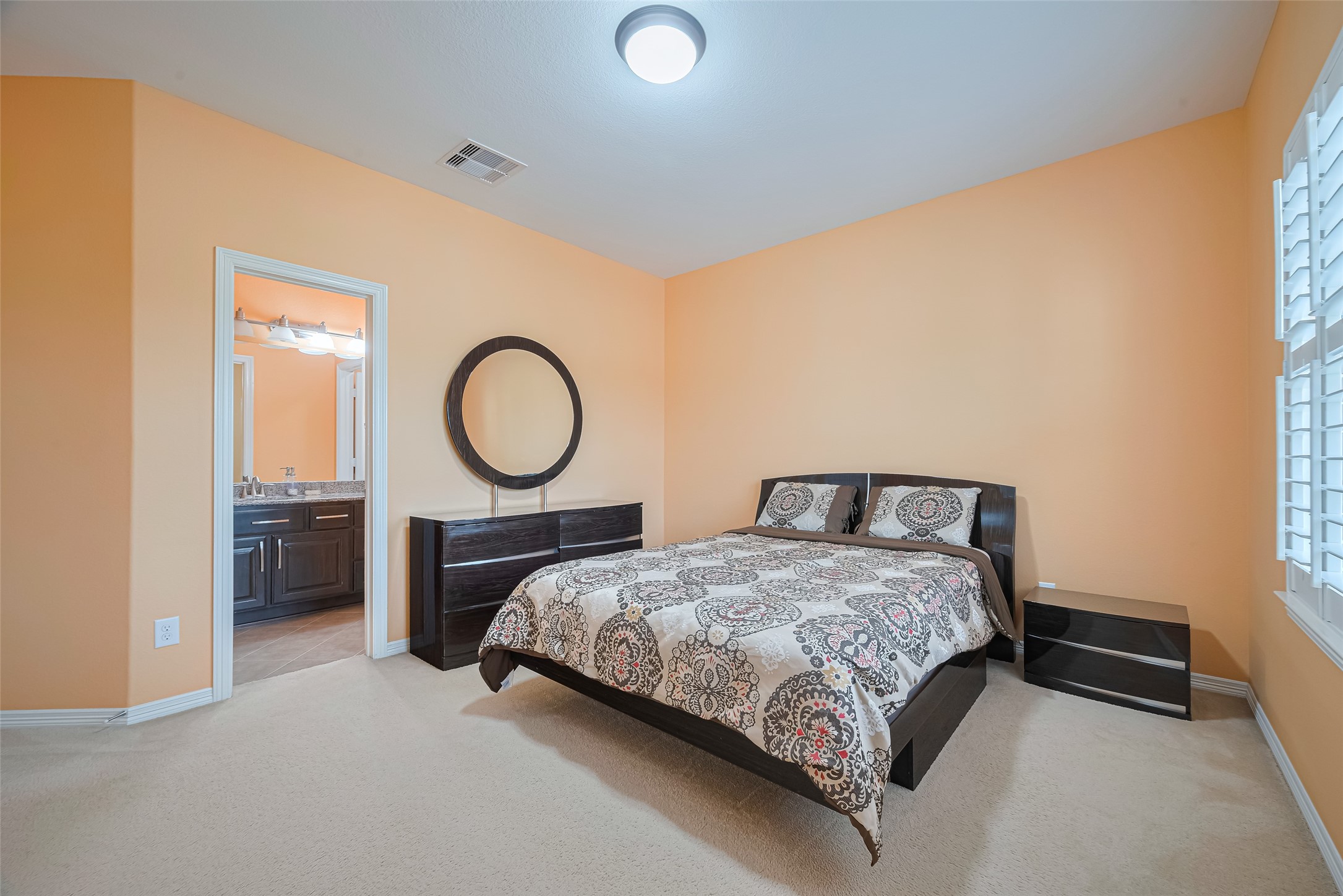 Another view of the spacious fourth bedroom, highlighting the comfortable layout, abundant natural light, and convenient access to the adjoining bathroom.