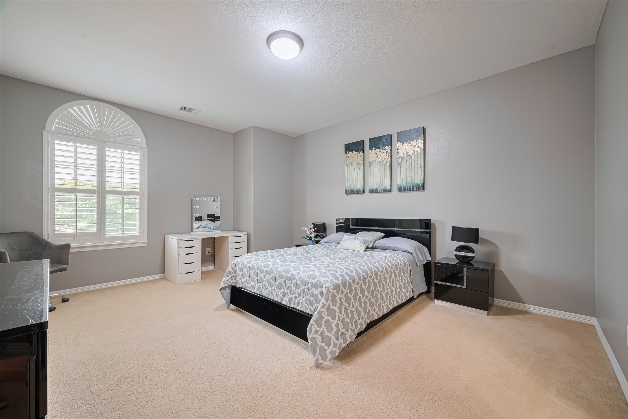 Spacious third bedroom featuring neutral tones, plush carpeting, ample natural light, and room for a dedicated vanity or workspace.