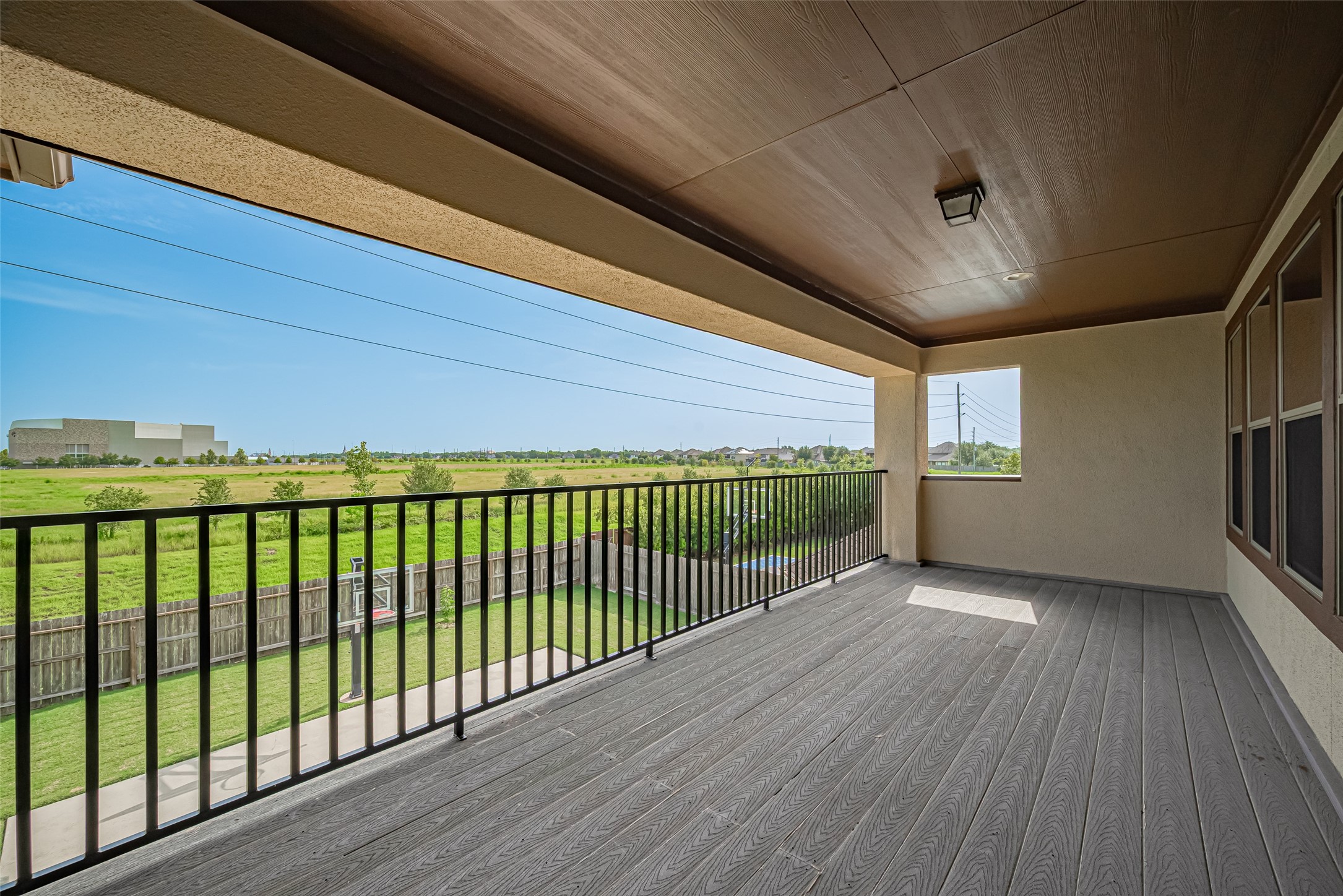 Another view of the expansive covered balcony, showcasing generous outdoor living space and peaceful open green views.