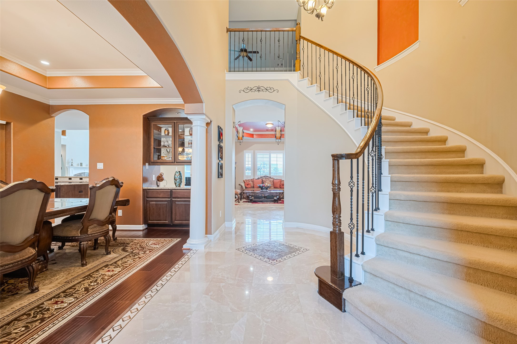 Impressive foyer showcasing polished tile flooring, a sweeping curved staircase, and an open view into the formal dining and living areas.
