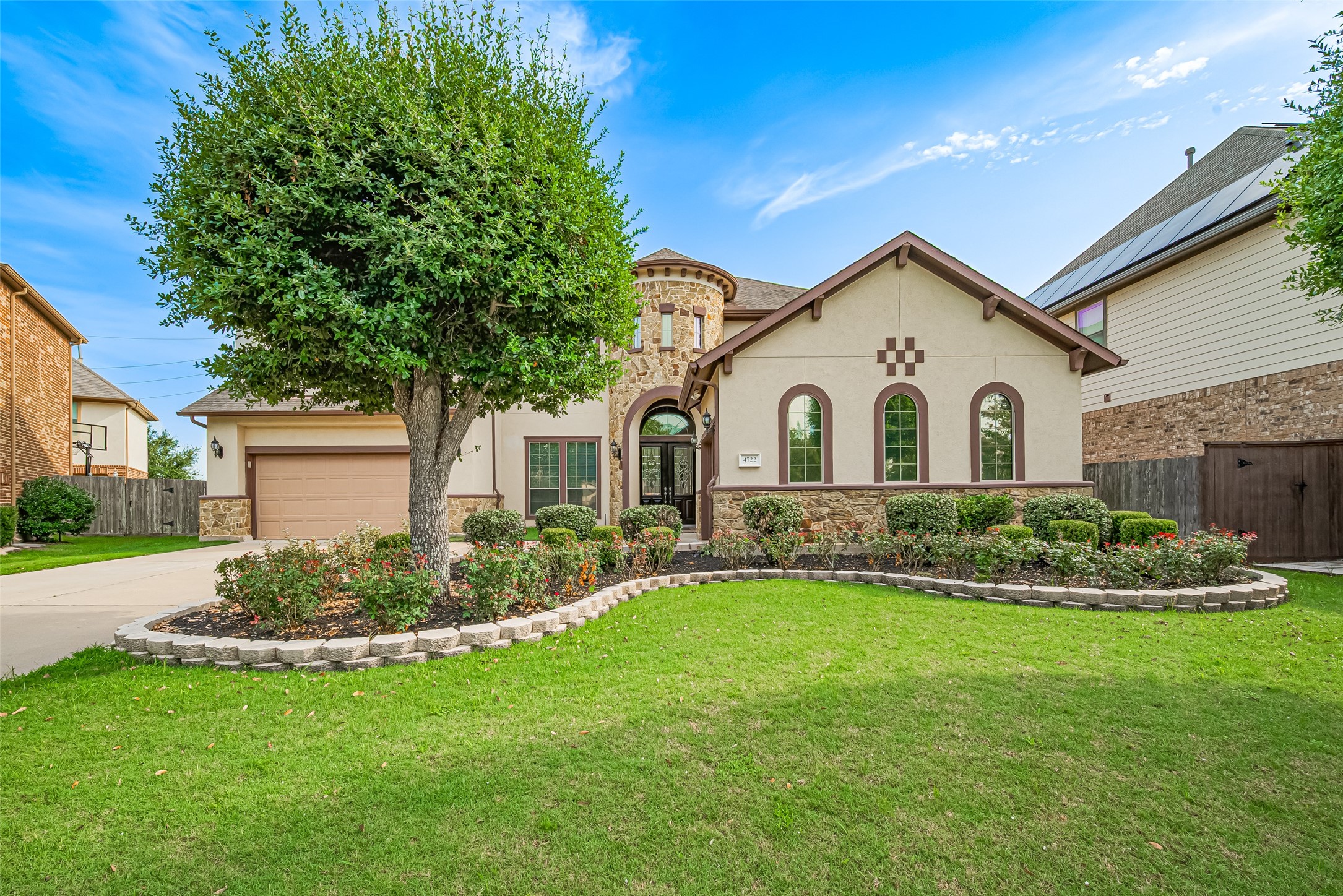 Striking front elevation showcasing refined stone accents, distinctive arched windows, manicured landscaping, and impressive curb appeal.