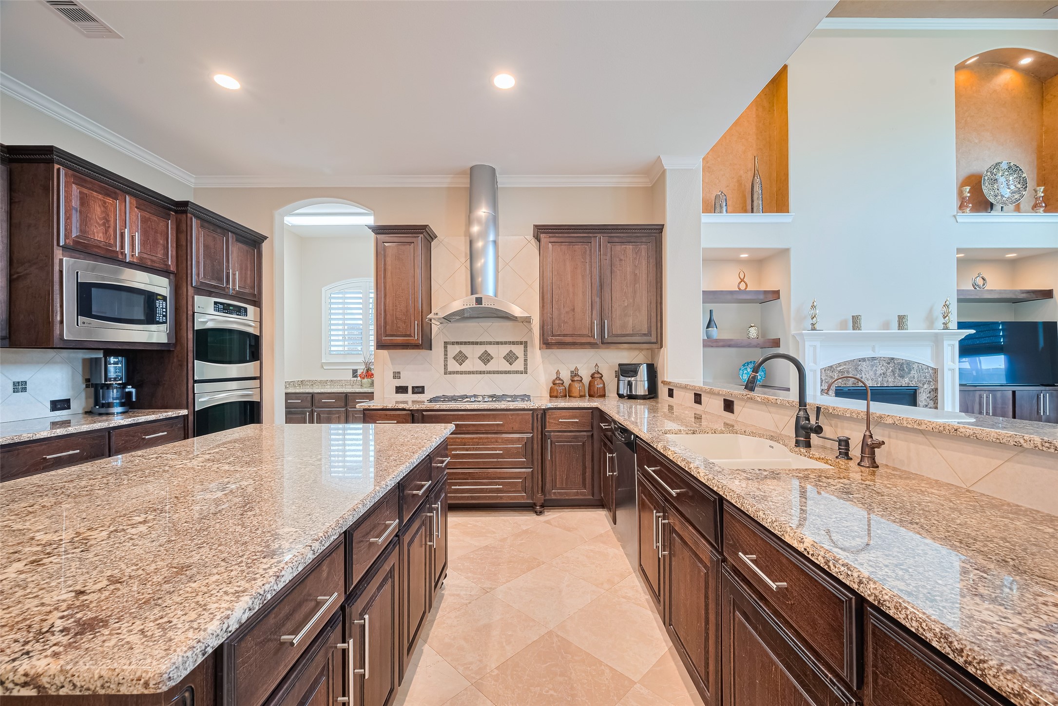 Closer kitchen perspective highlighting the gas cooktop, double ovens, deep countertops, and convenient pass-through overlooking the family room.