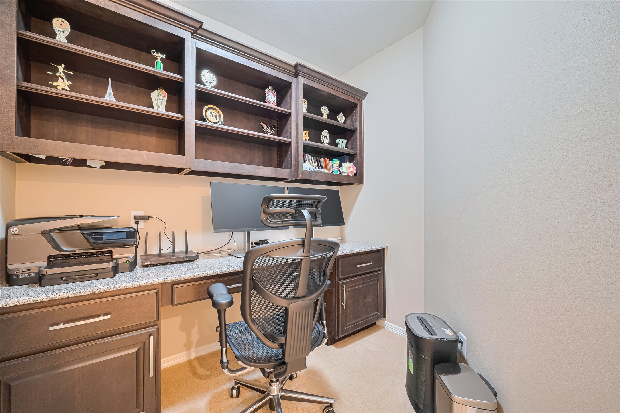 Private home office with a built-in workstation, granite desktop, and extensive shelving for organized storage and display.