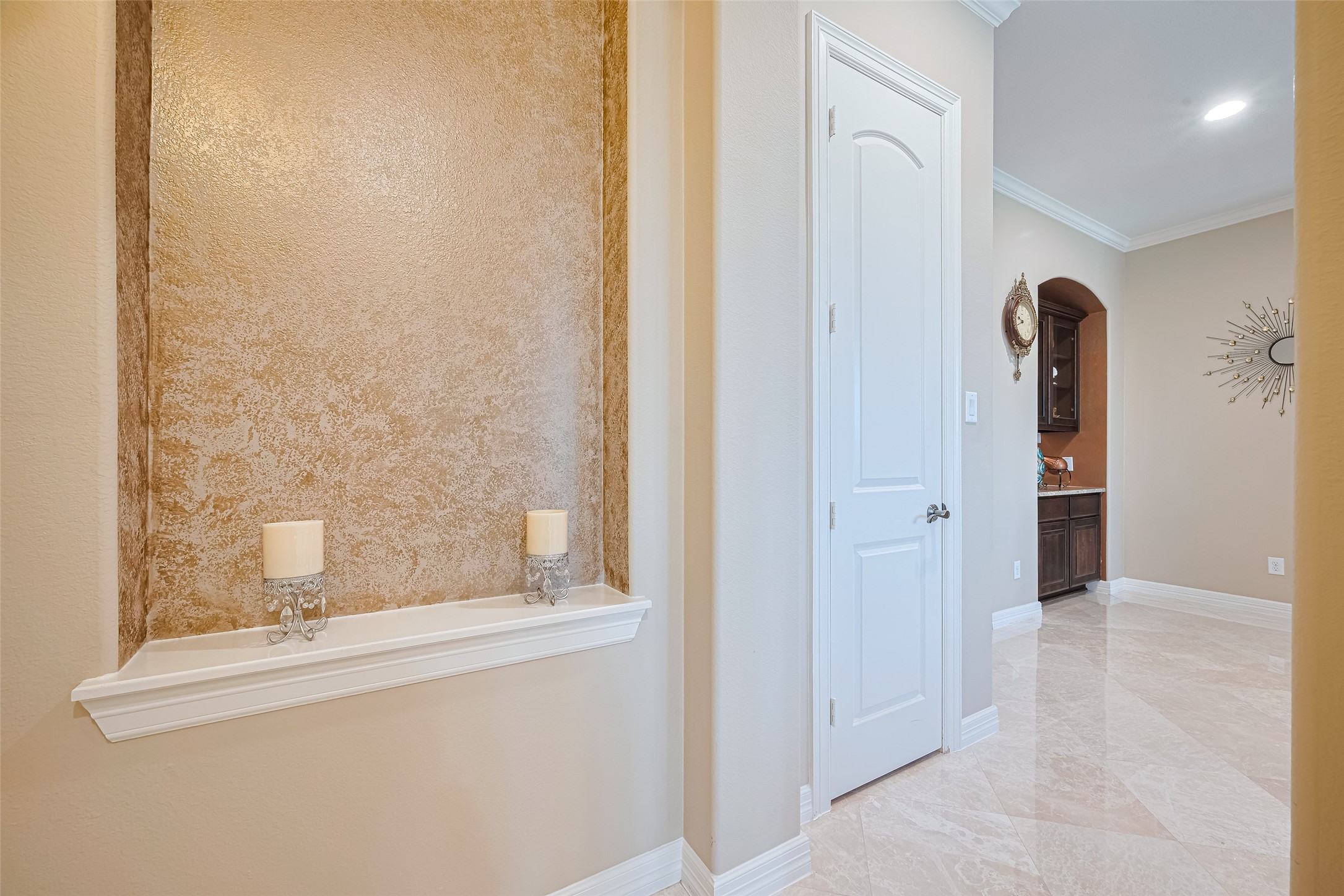 Refined interior hallway accented by a decorative wall niche, polished tile flooring, and graceful arched transitions.