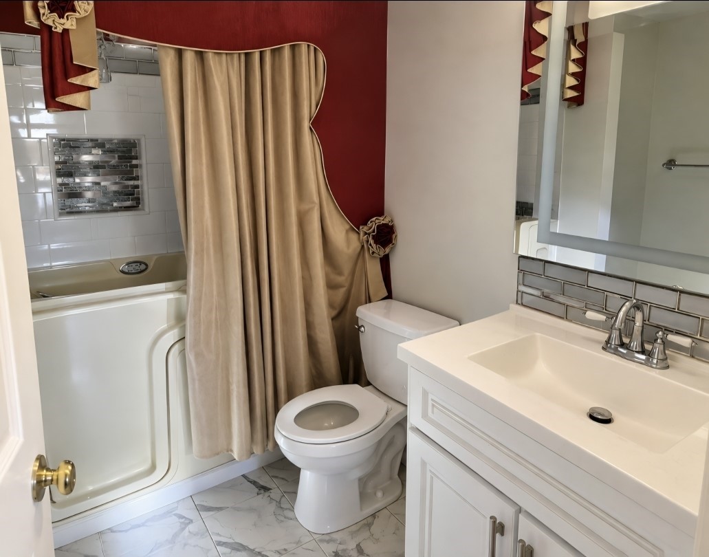 Charming bathroom featuring a modern vanity with sleek fixtures, an elegant walk-in tub, and stylish tile accents for a touch of luxury.