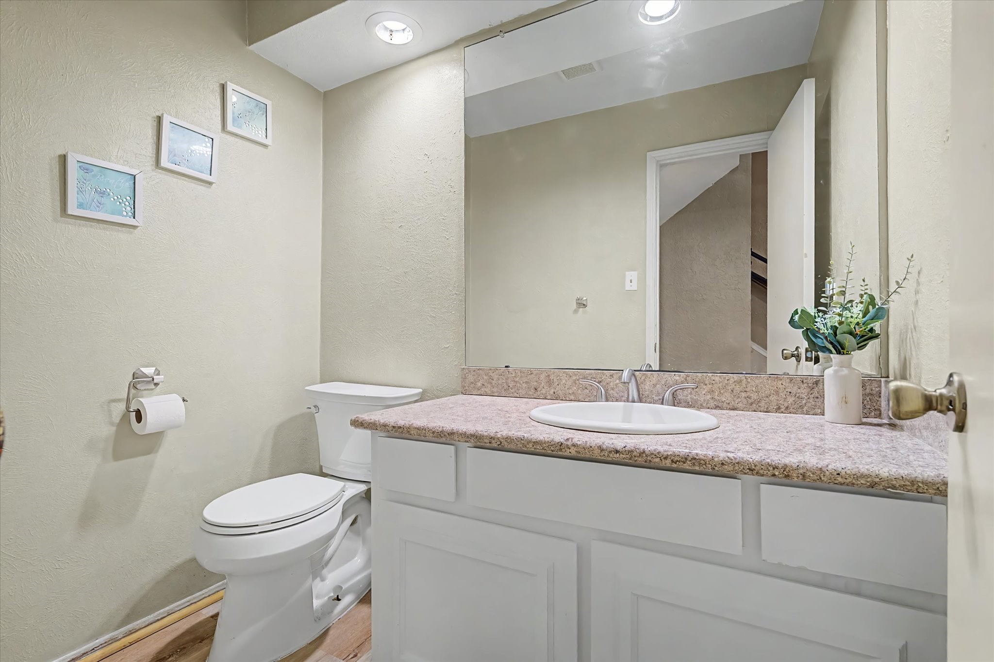 Convenient half bath with vanity, large mirror, and recessed lighting.
