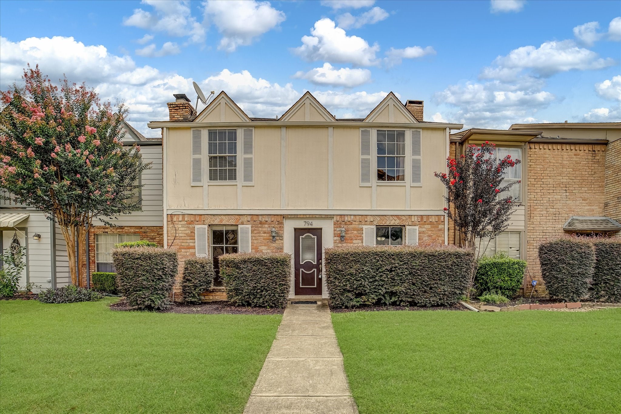 Welcome to 794 Thicket! A two-story townhome featuring a brick and stucco exterior, mature landscaping, and a welcoming front walkway.