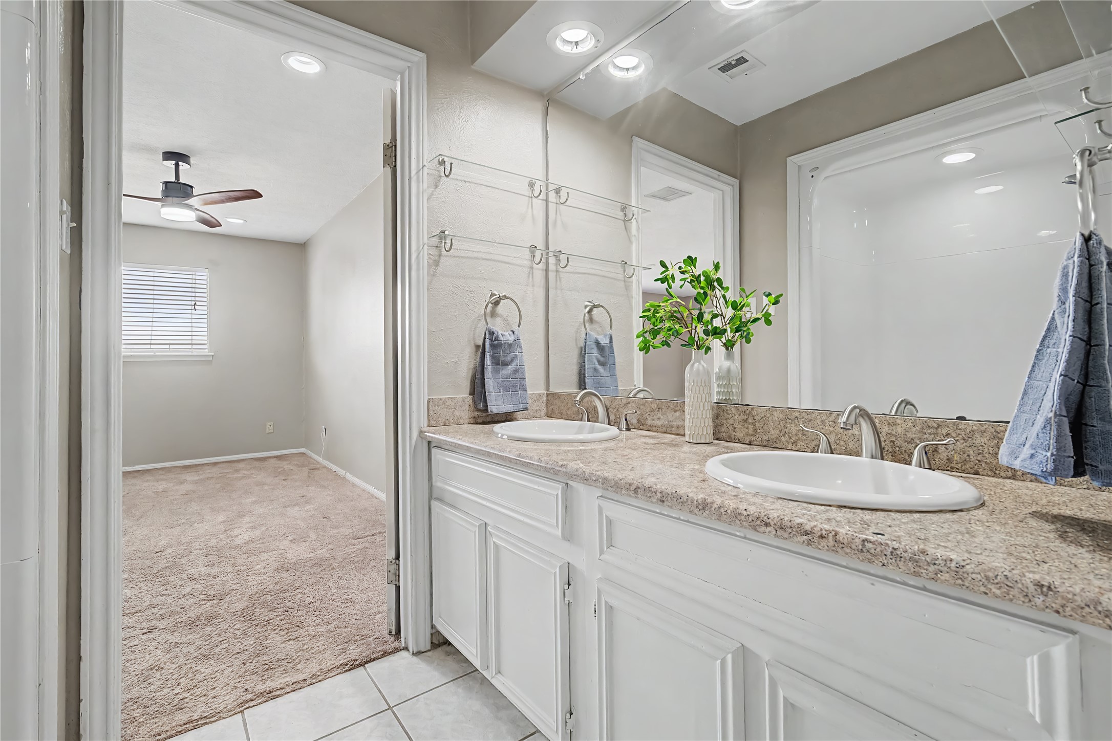 The primary bathroom features double-sink vanity with generous counter space, large mirror, and tile flooring.