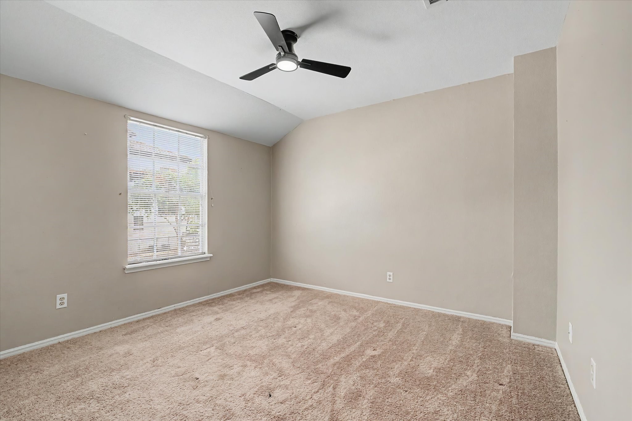 Spacious bedroom with carpet flooring, ceiling fan, and natural light.