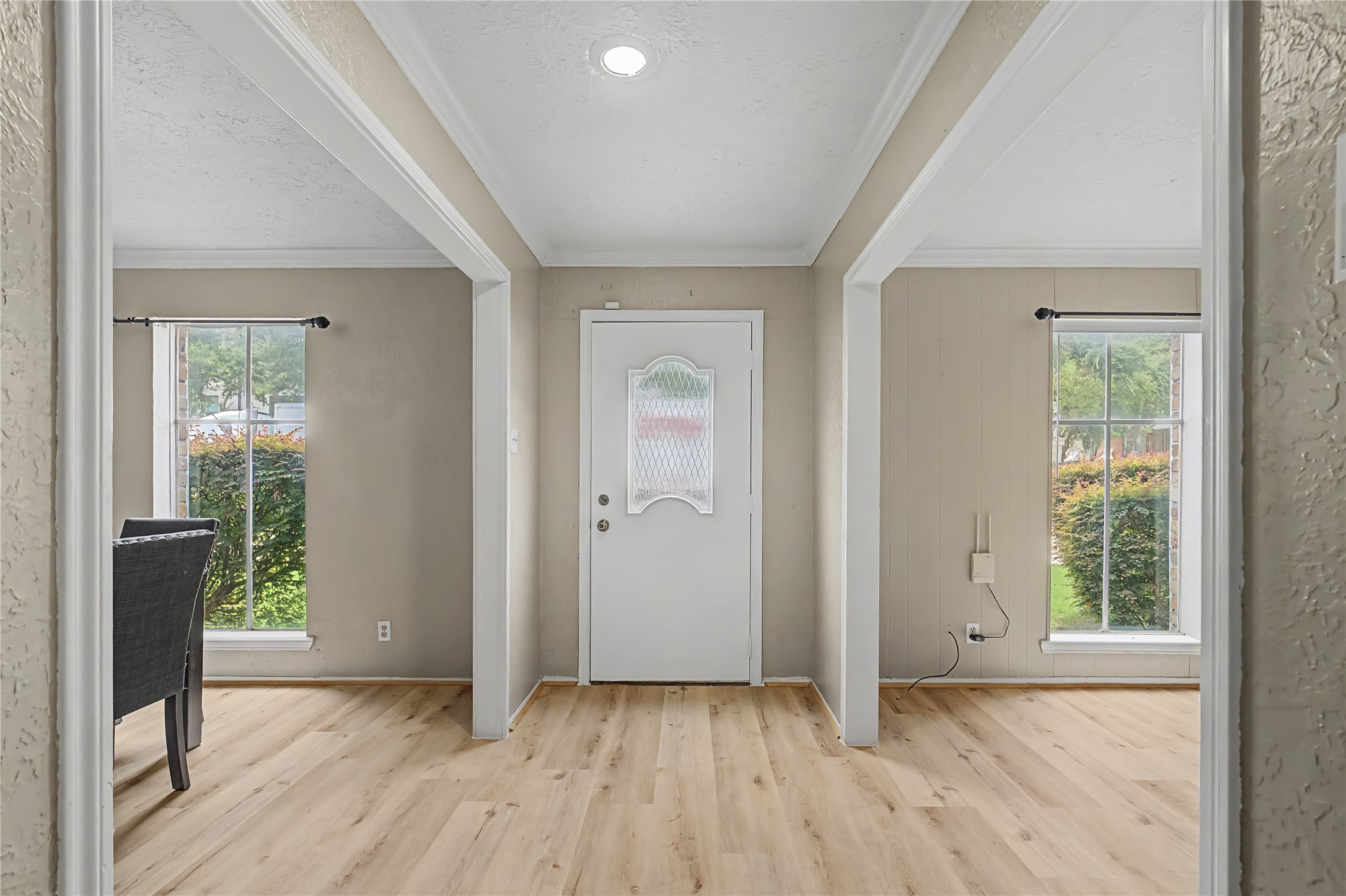 Bright entryway with updated flooring, crown molding, and openings to adjoining rooms.