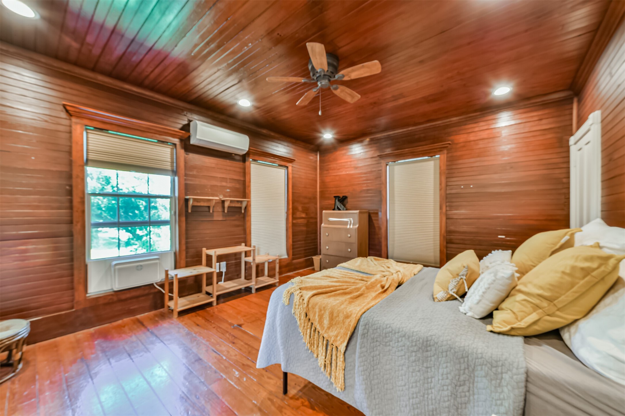 Upstairs primary bedroom wrapped in warm wood creates a cozy retreat with loads of historic personality.