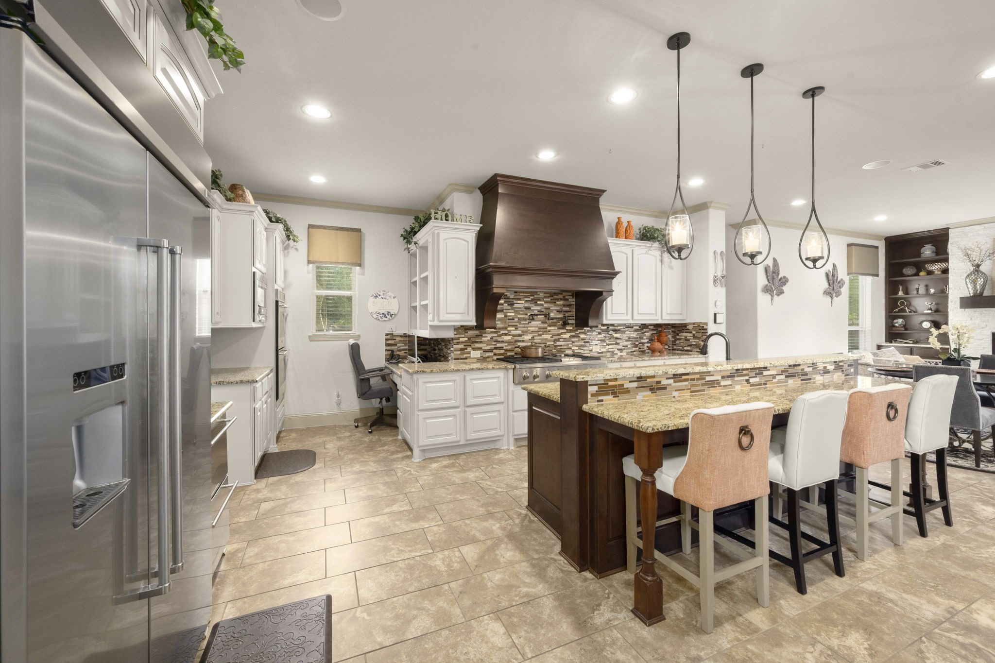 This modern kitchen includes stainless steel appliances, a large island with stylish pendant lighting, a spacious breakfast bar, a walk-in pantry and a secondary kitchenette.