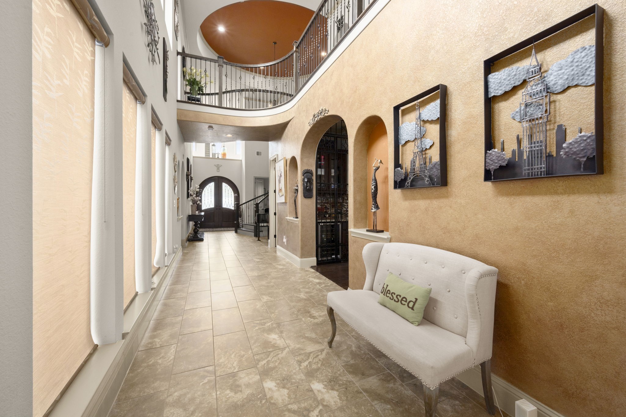 This hallway features the high ceilings, a grand staircase, large windows and an entryway to the designated dining room.