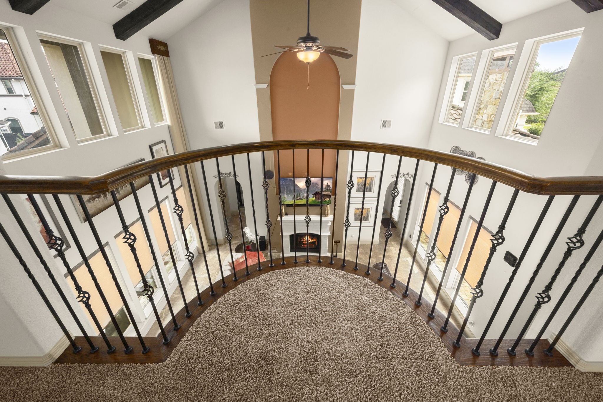 This photo features an elegant, open-concept home with a view from the loft area overlooking the spacious living area on the first floor.