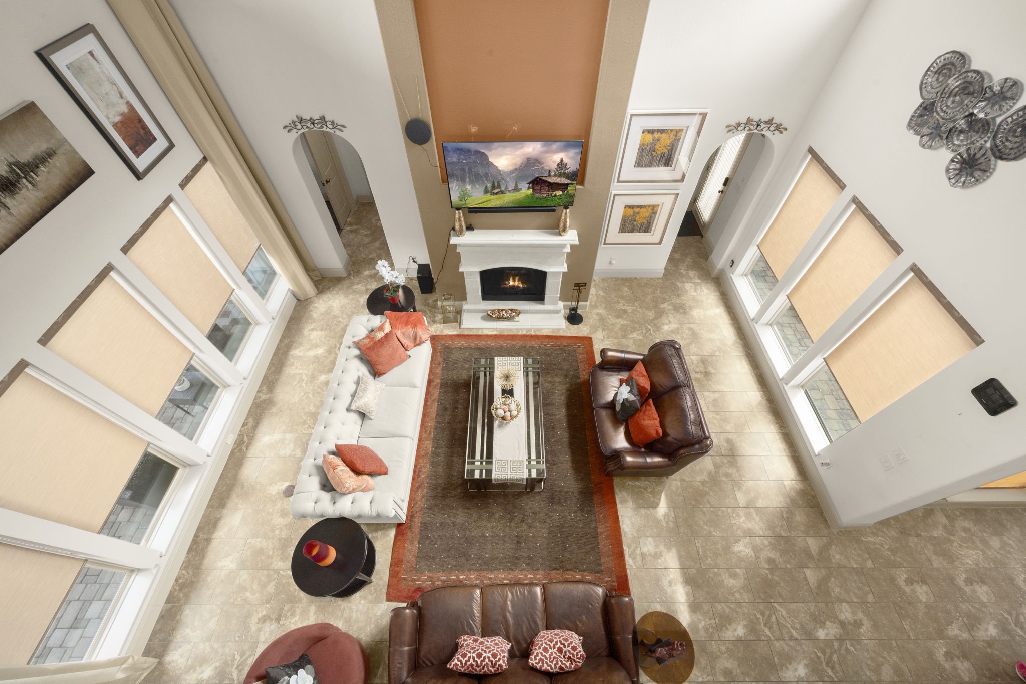 This spacious living room features high ceilings, large windows with abundant natural light, and a central fireplace.