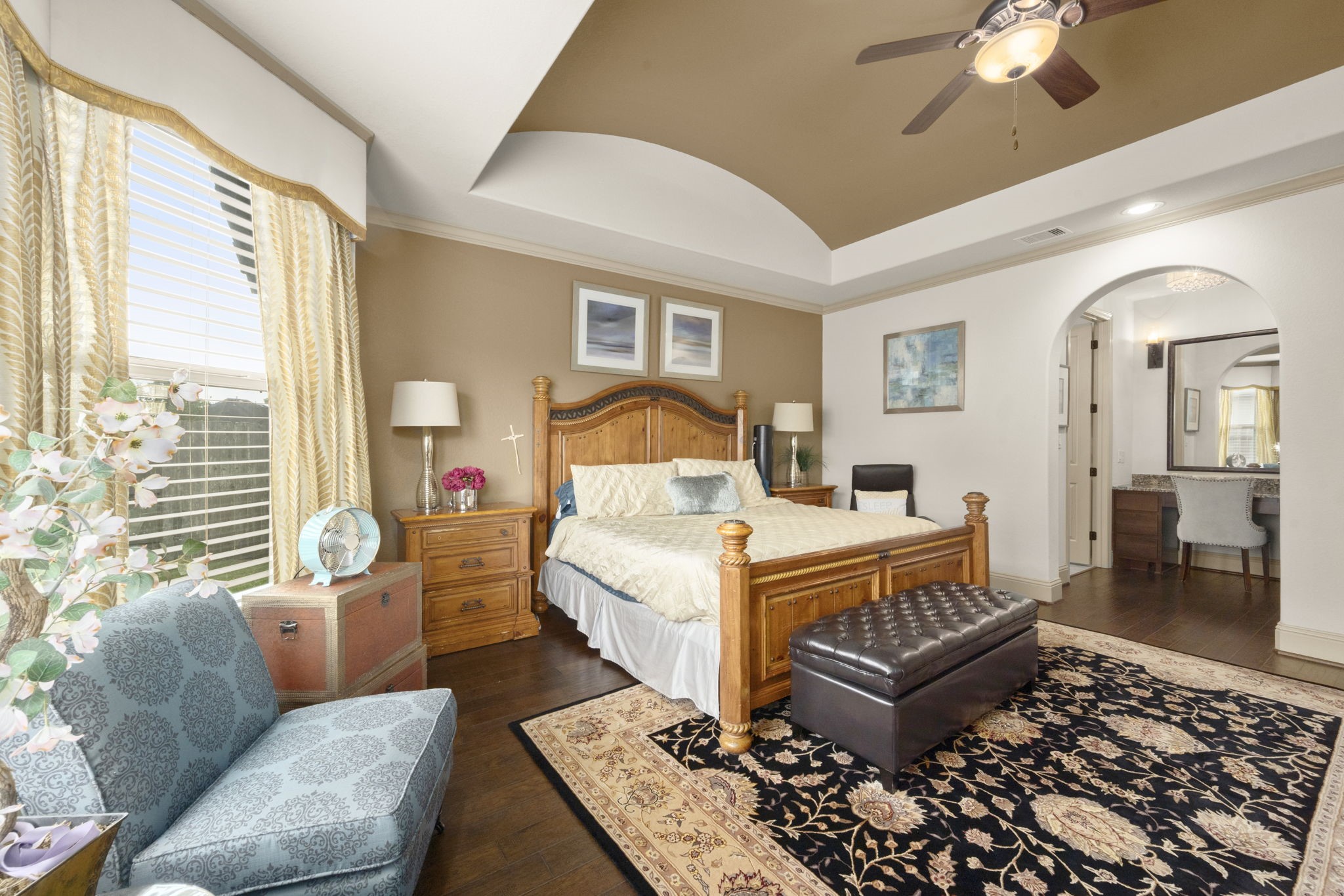 This spacious primary bedroom connects to a well-appointed ensuite bathroom through an arched doorway.