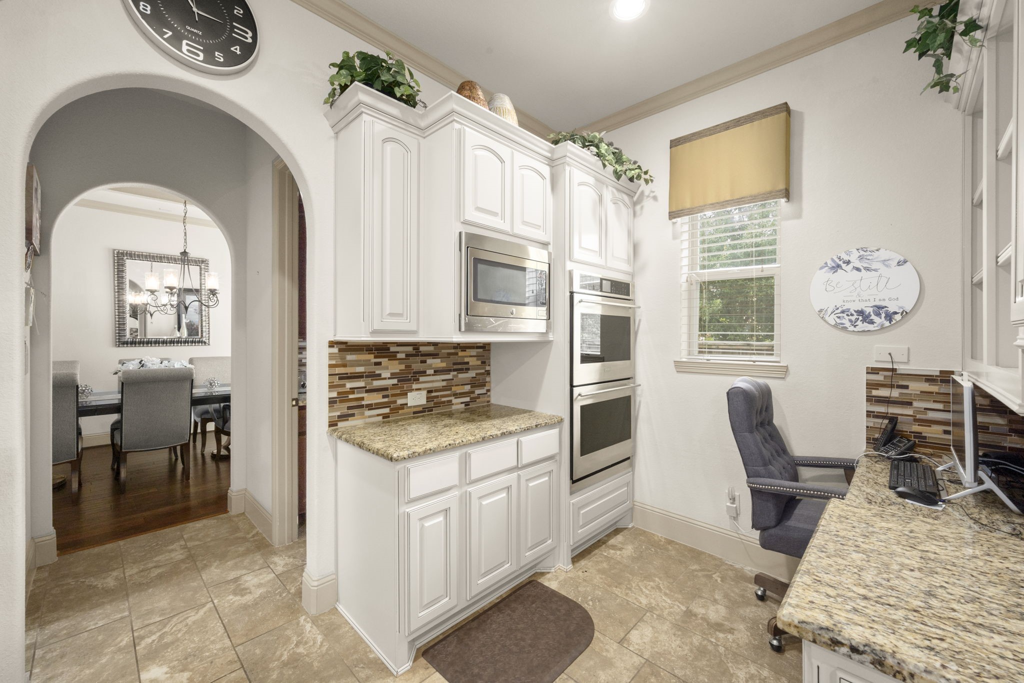 This area of the kitchen features a cozy workspace and an arched walkway that leads to a dining room, walk-in pantry and secondary kitchenette.